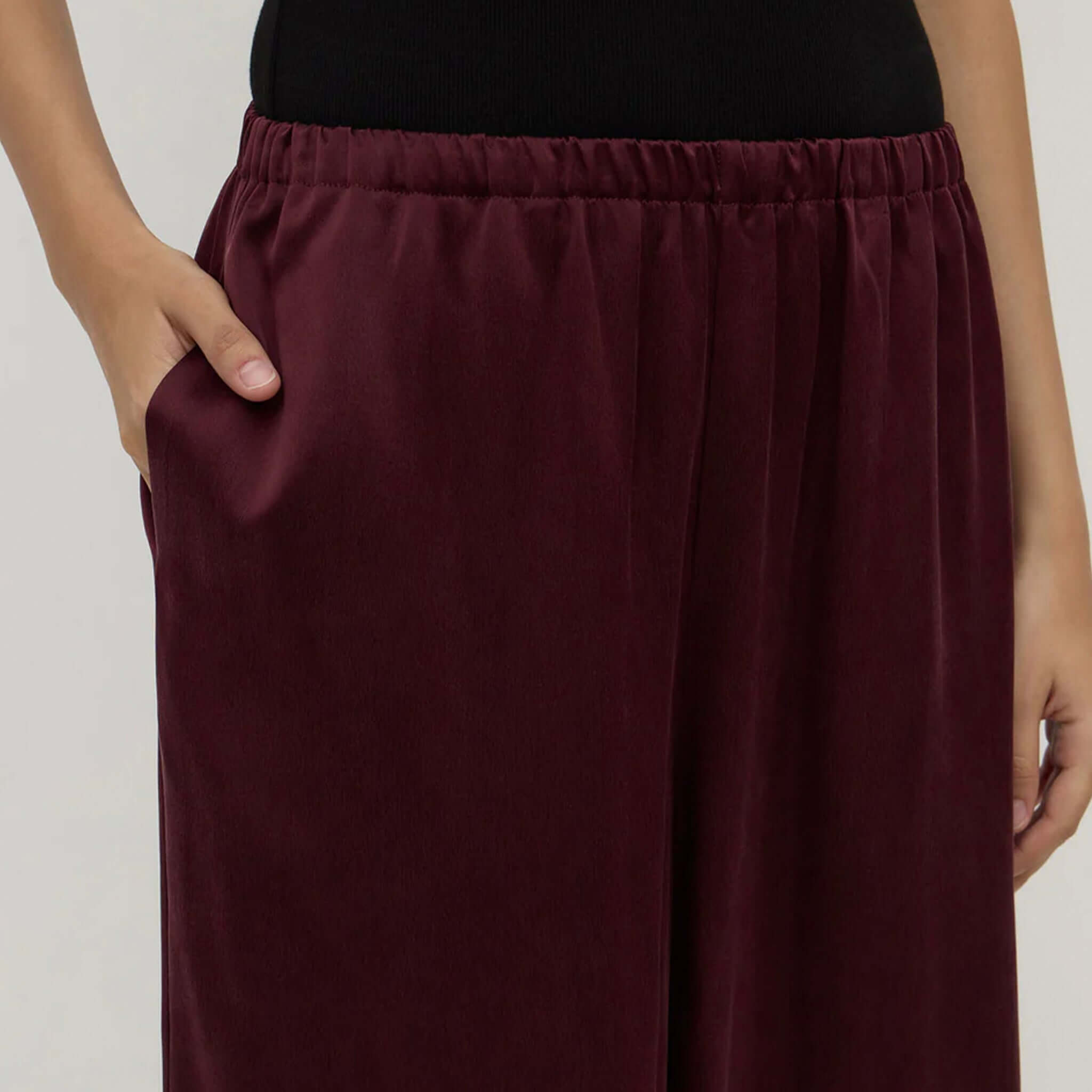 Alt Tag: Assembly Label Pippa Silk Pants - Merlot close-up of elasticated waistband, fluid wide-leg silk fabric and side seam pocket detail
