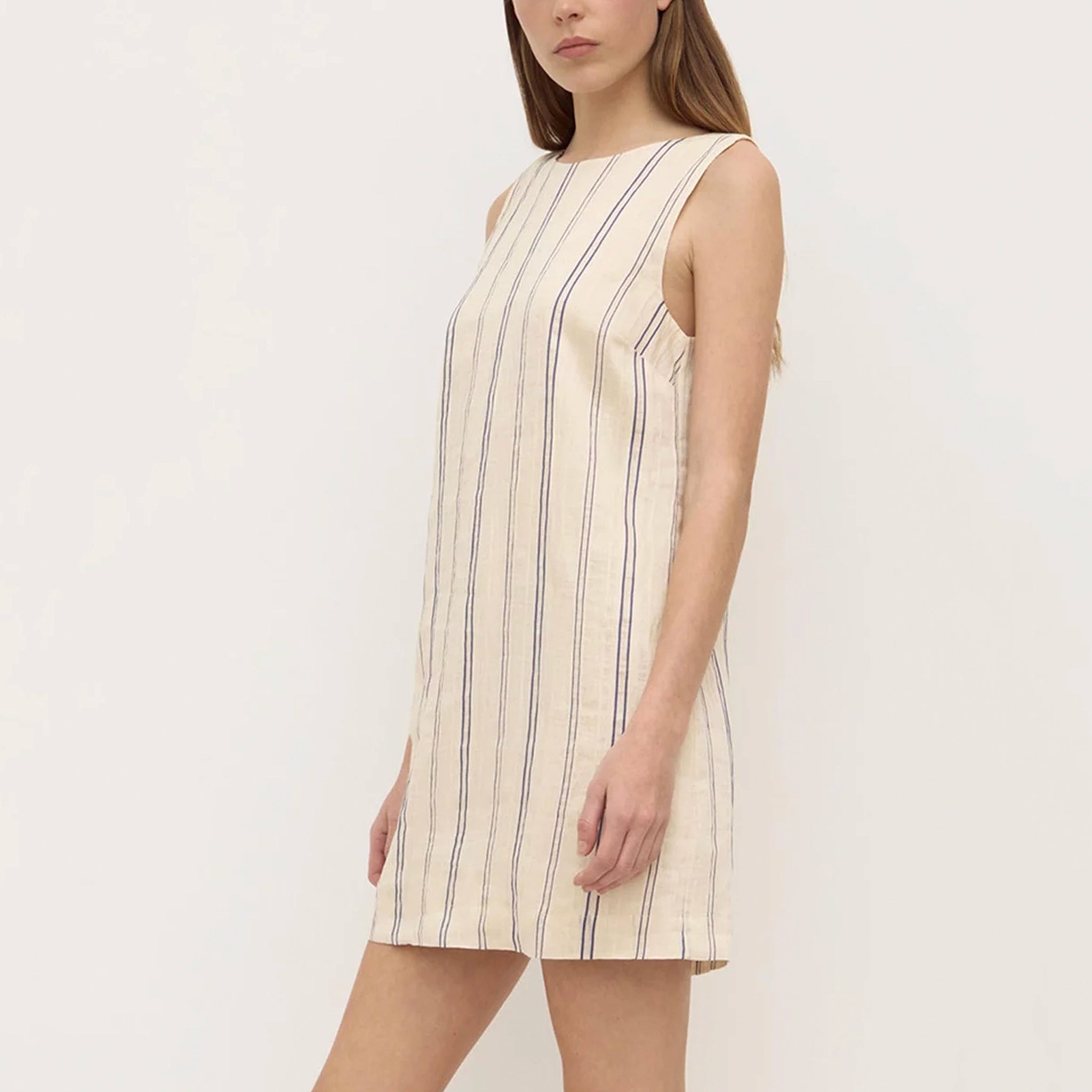 Woman wearing a sleeveless dress with vertical stripes on a plain background