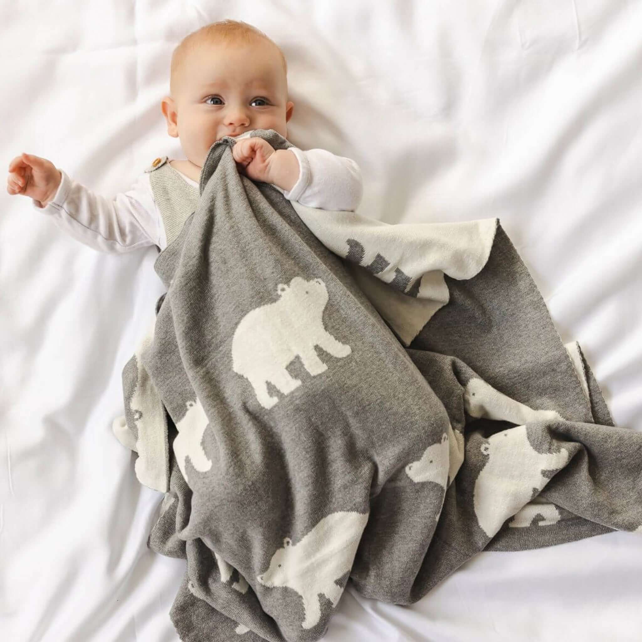 Baby Cotton Piper Blanket - Polar Bear wrapped around a baby, showcasing its charming polar bear motifs in grey marle.