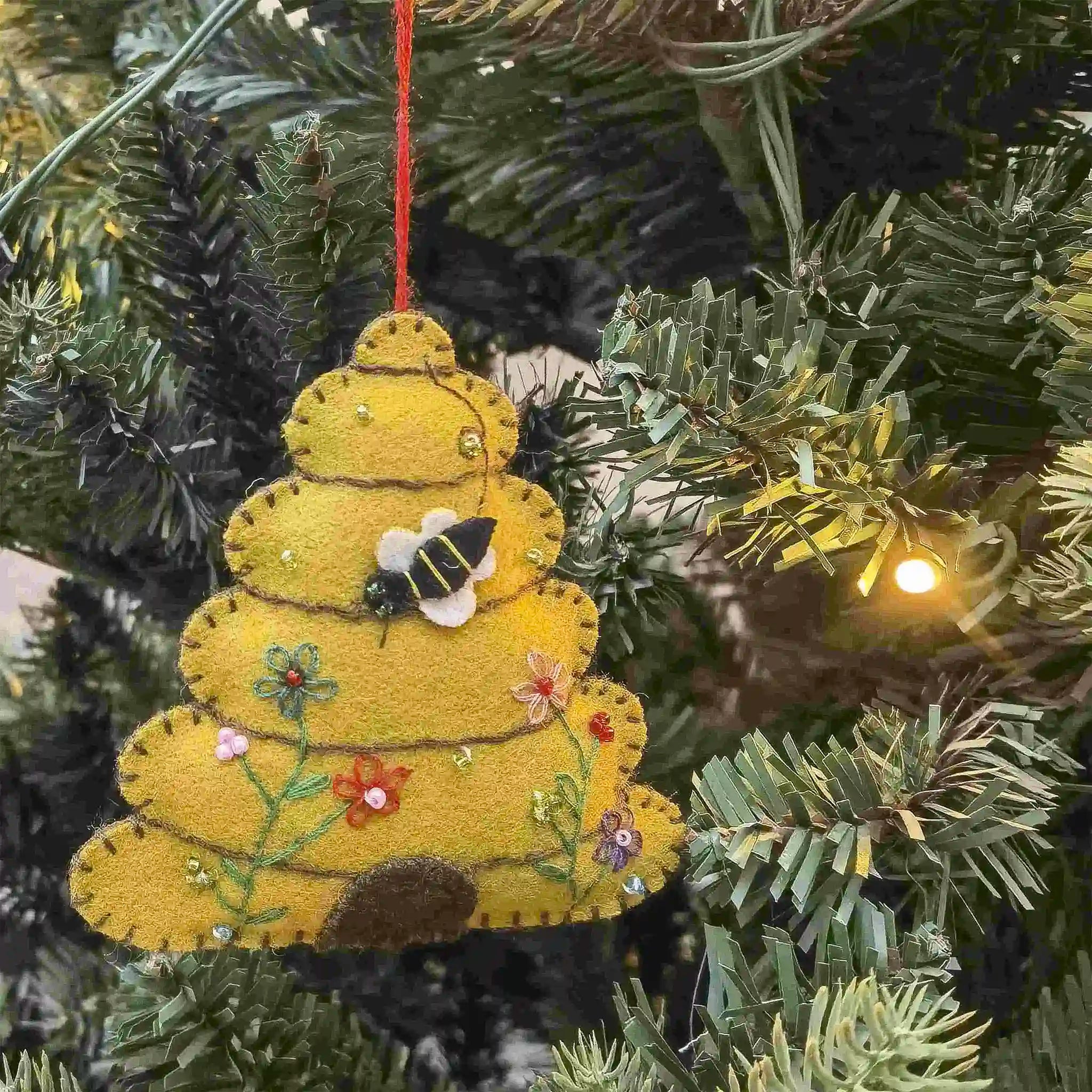 Decorative ornament shaped like a beehive with a bee on a Christmas tree.