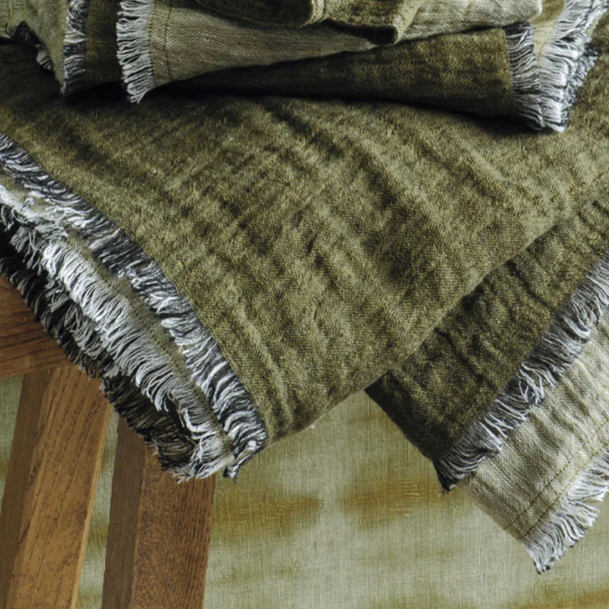Stack of green plaid hand towel with fringes on a wooden surface