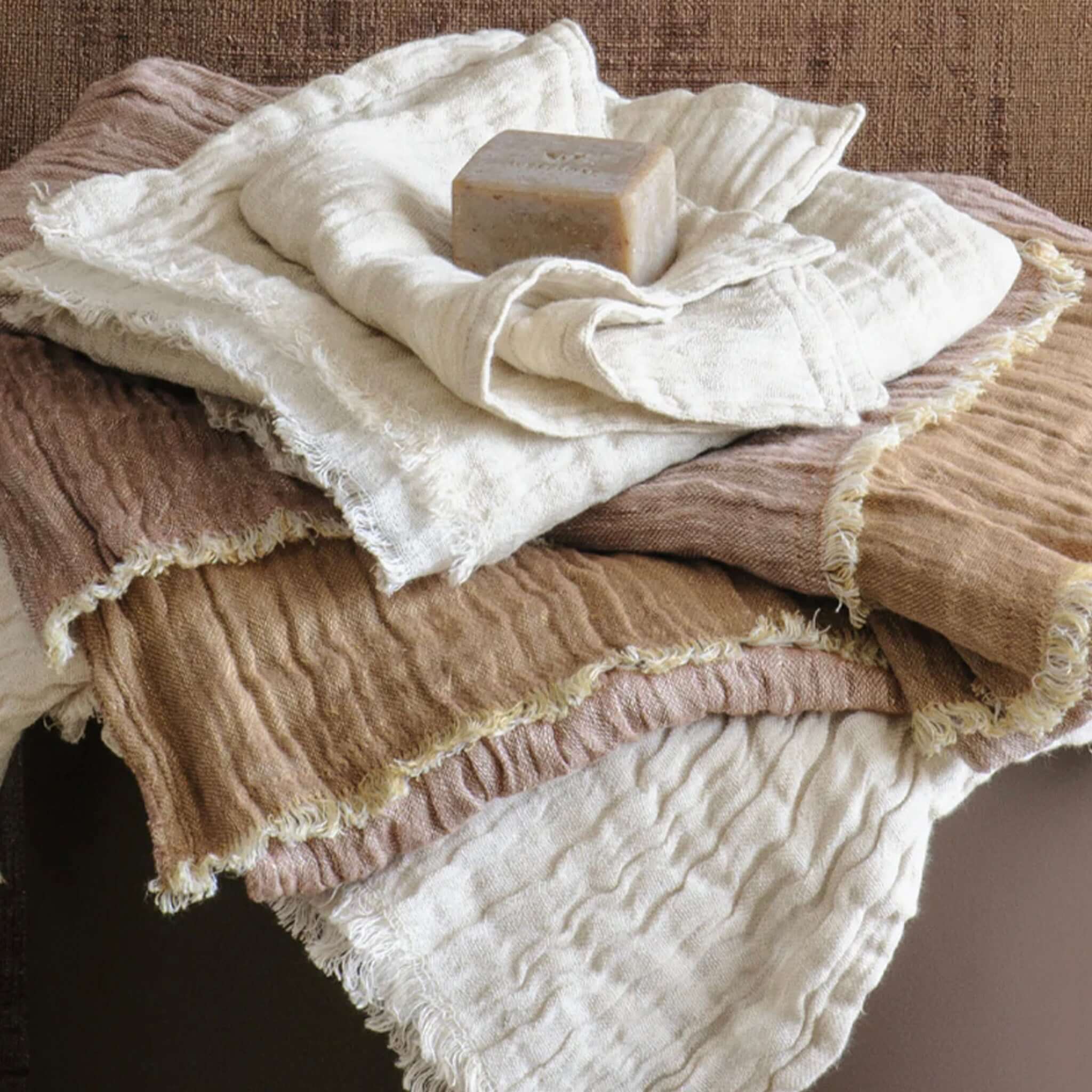 Stack of textured towels with a bar of soap on a wooden surface