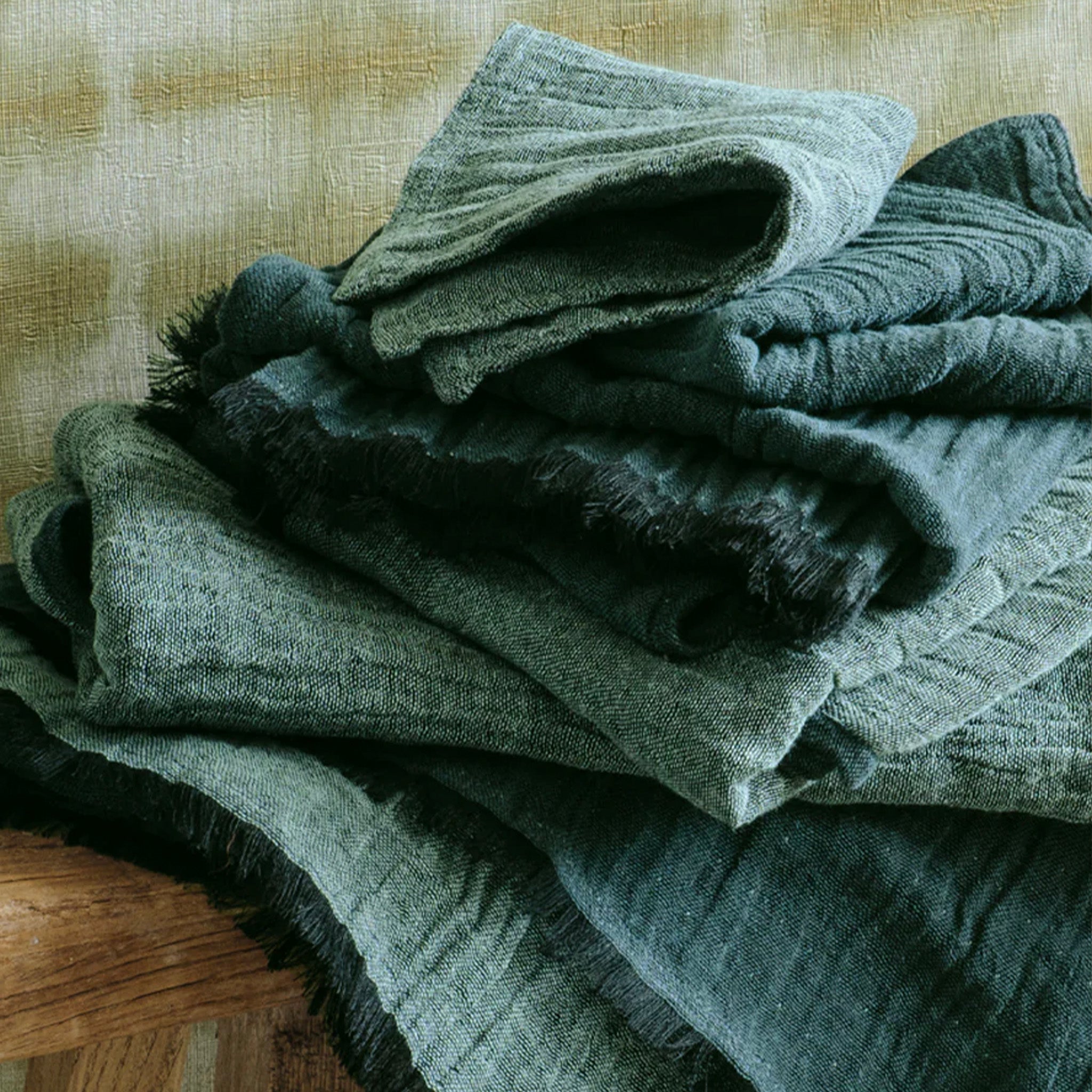 Stack of green textured wash cloths items on a wooden surface