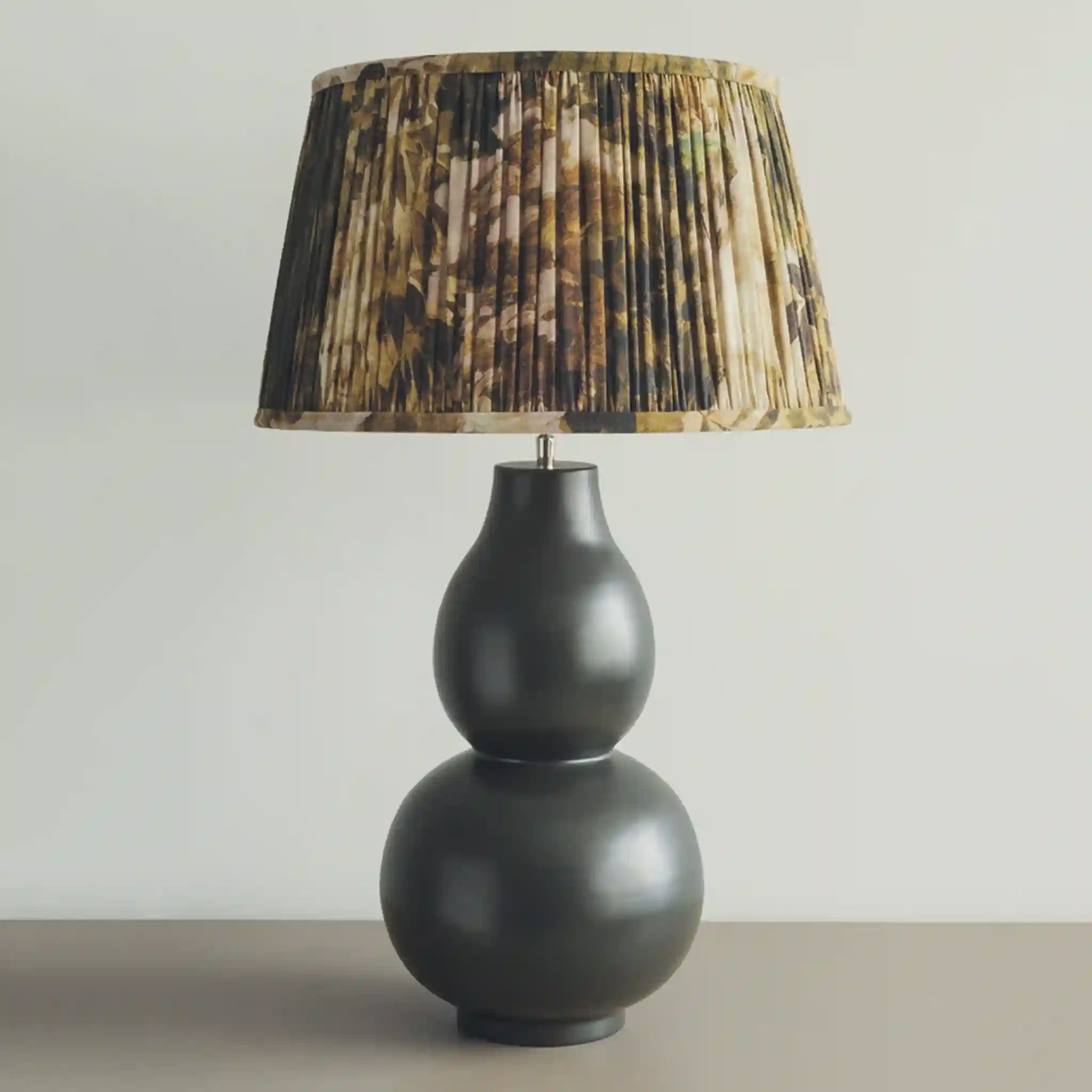 Black lamp with a pleated brown and black lampshade on a neutral background