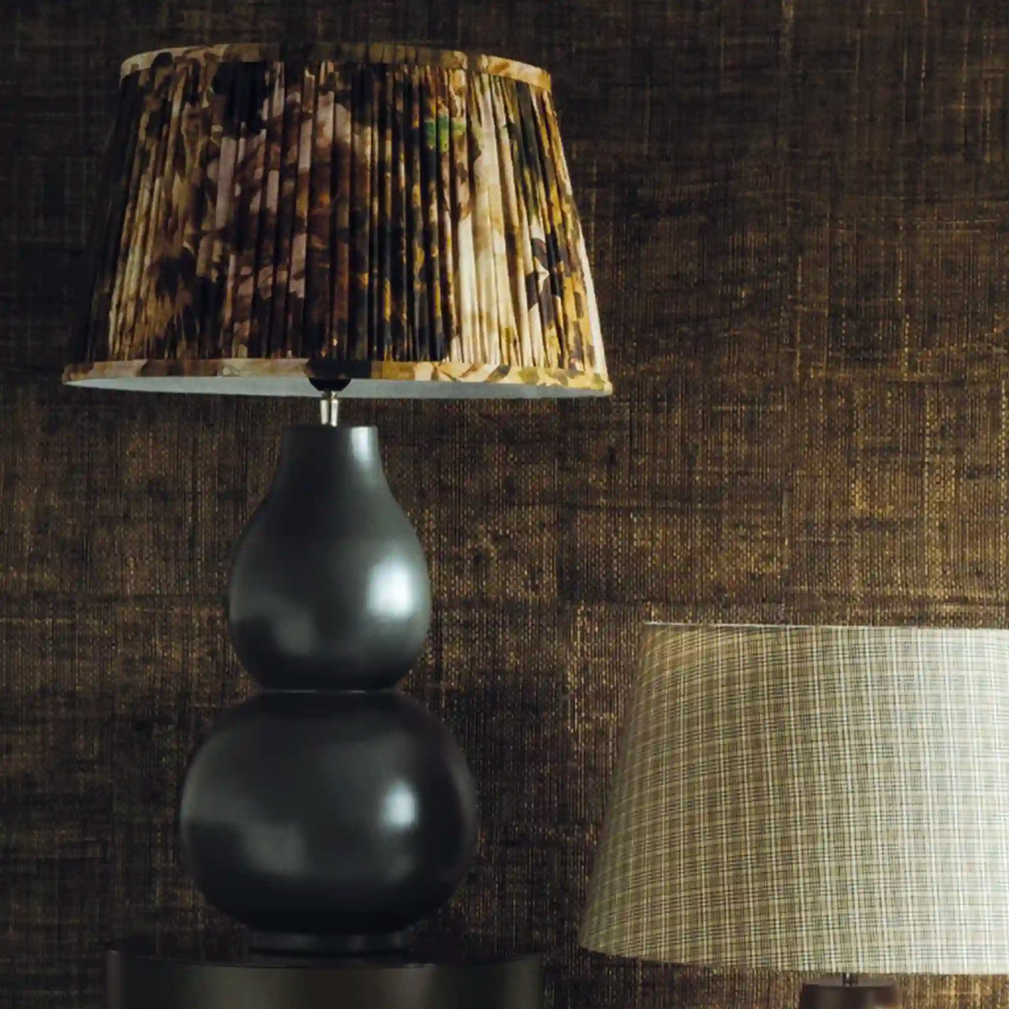 Decorative lamp with a patterned shade against a textured brown wall.