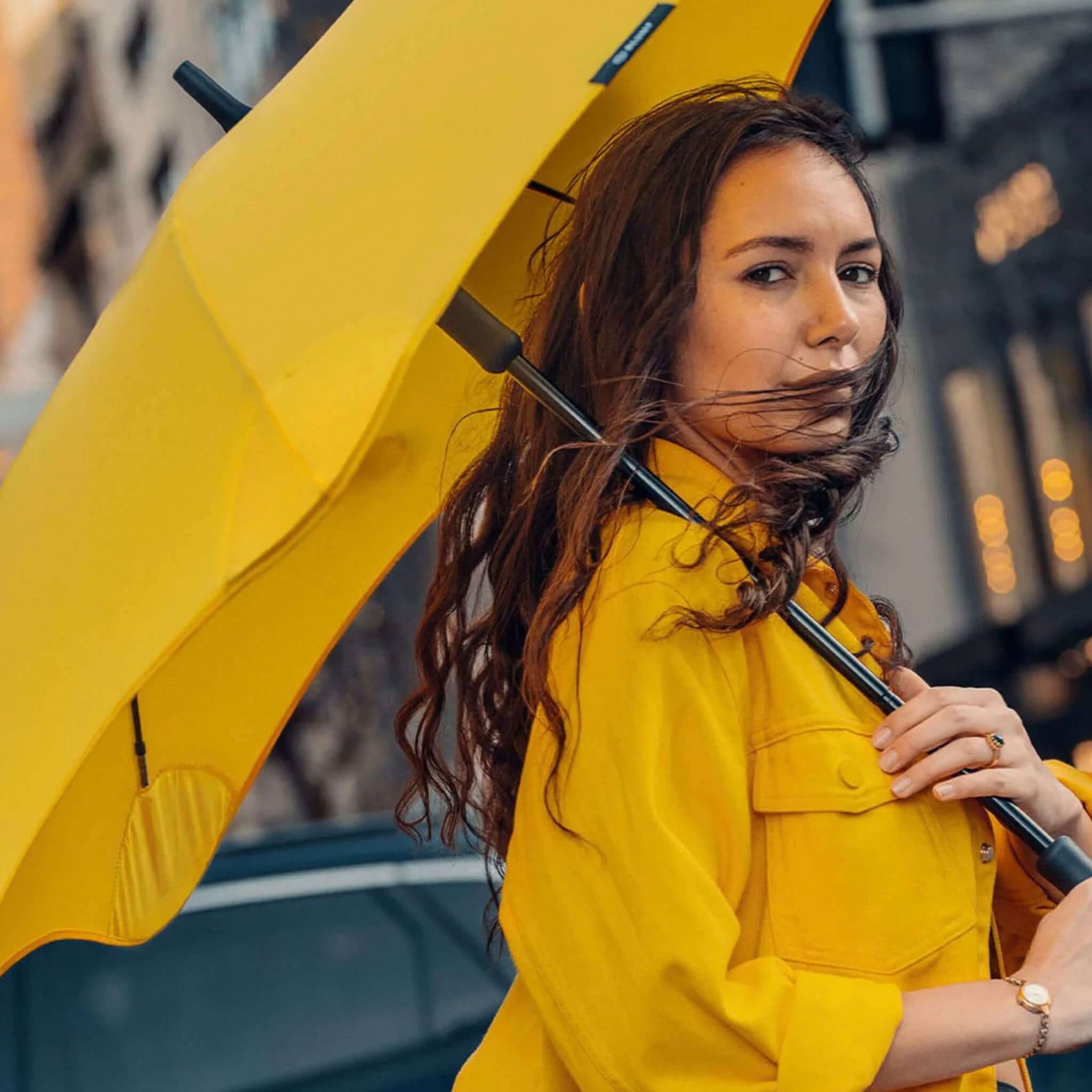 Alt Tag: Blunt Classic Core Range Umbrella held by woman in yellow coat, full-size high-performance canopy for rainy city streets