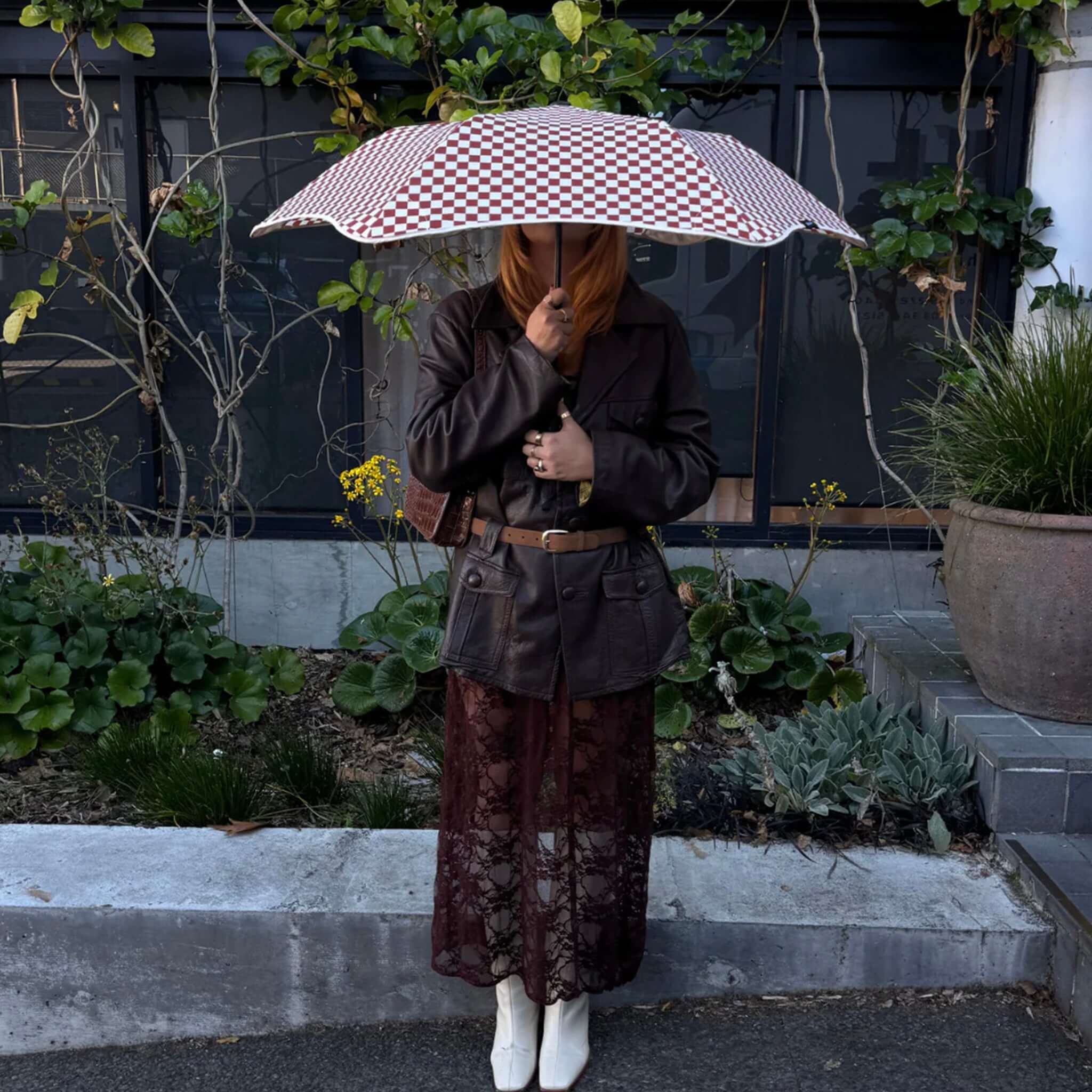 Person standing with a Blunt Metro Umbrella - Clay Check Limited Edition in a garden setting.