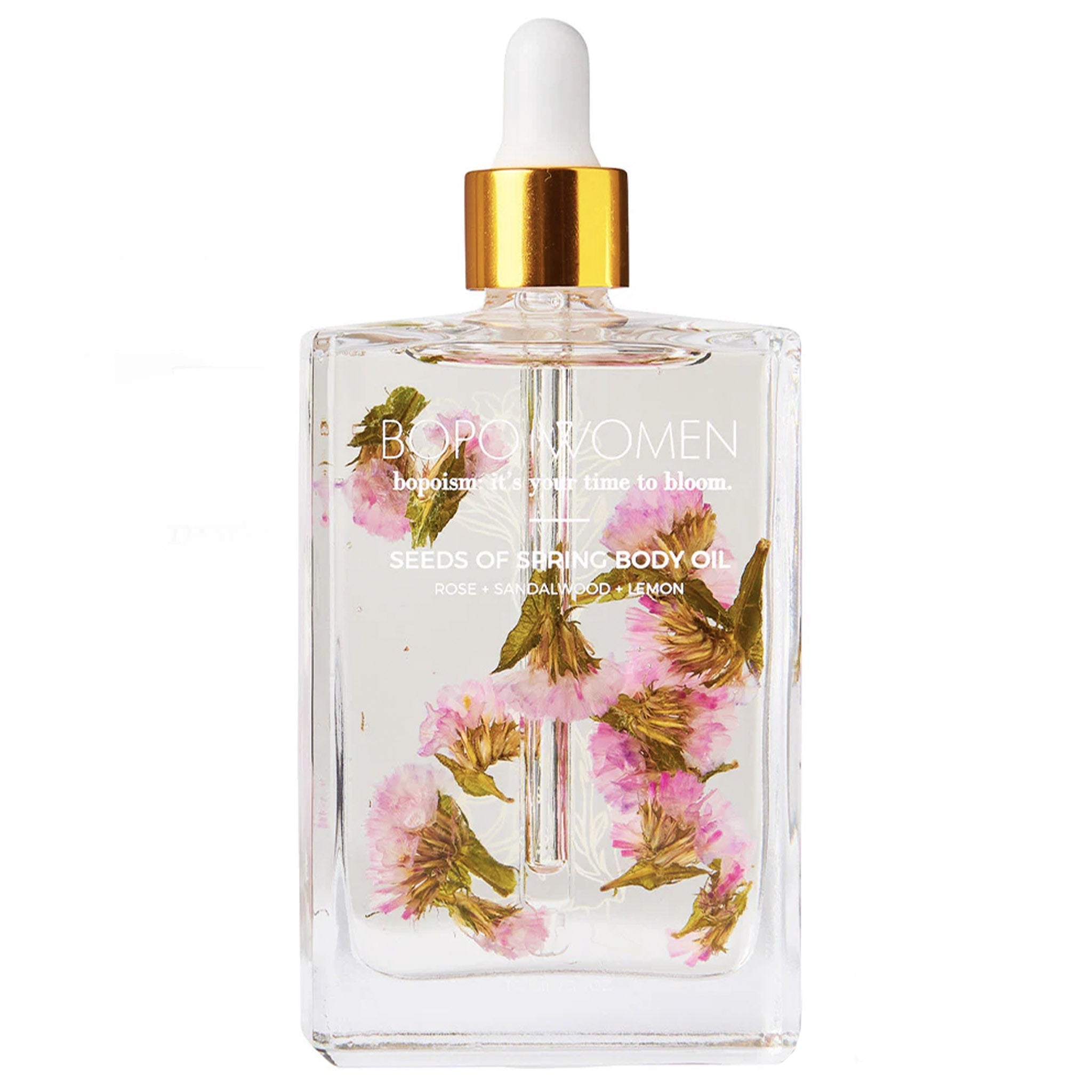 Bottle of body oil with floral design and gold cap on a white background