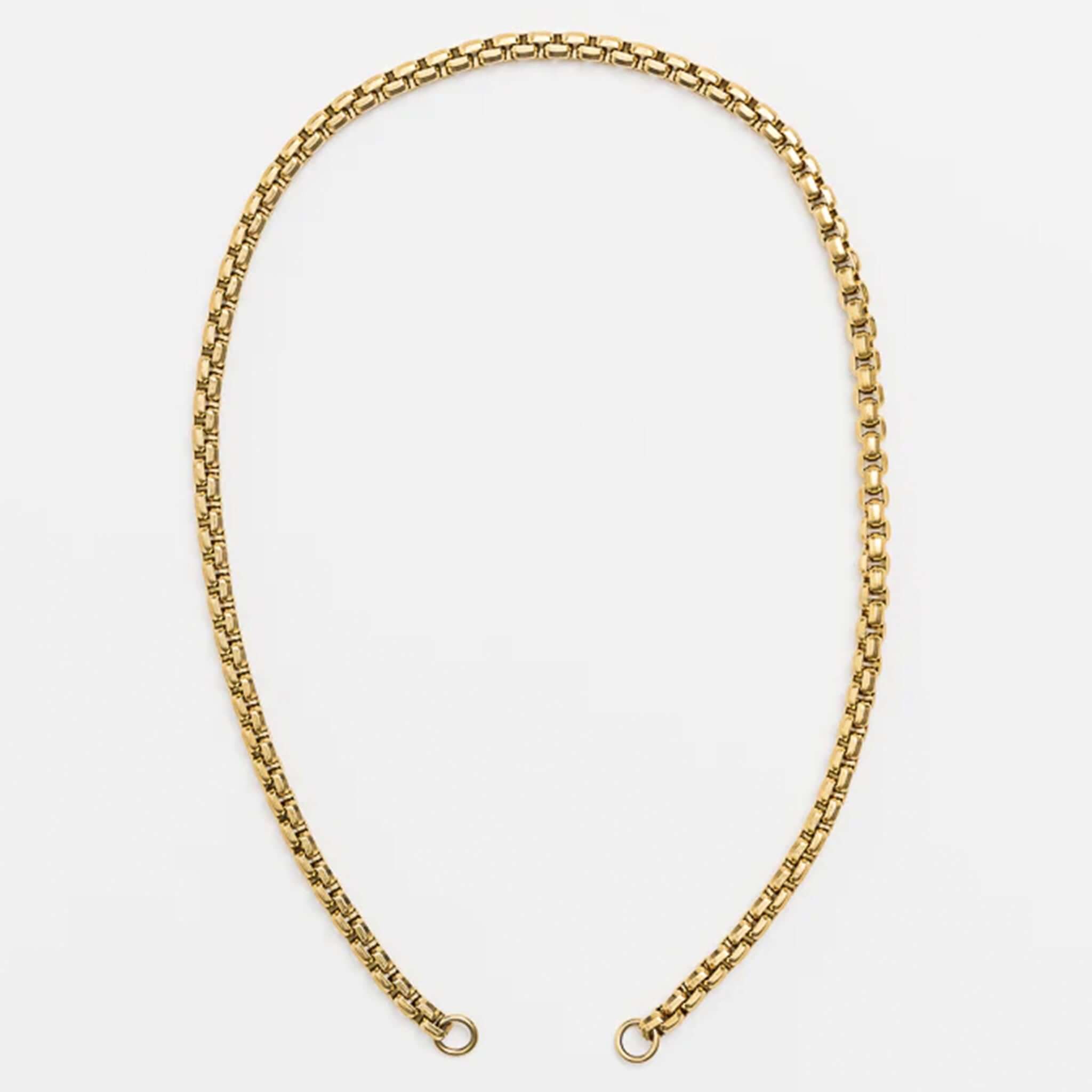 Gold chain necklace on a light gray background