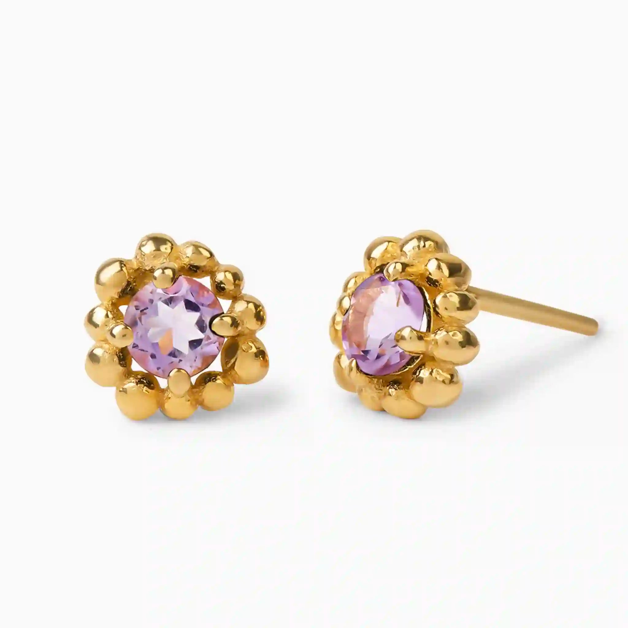 Gold earrings with purple gemstones on a white background