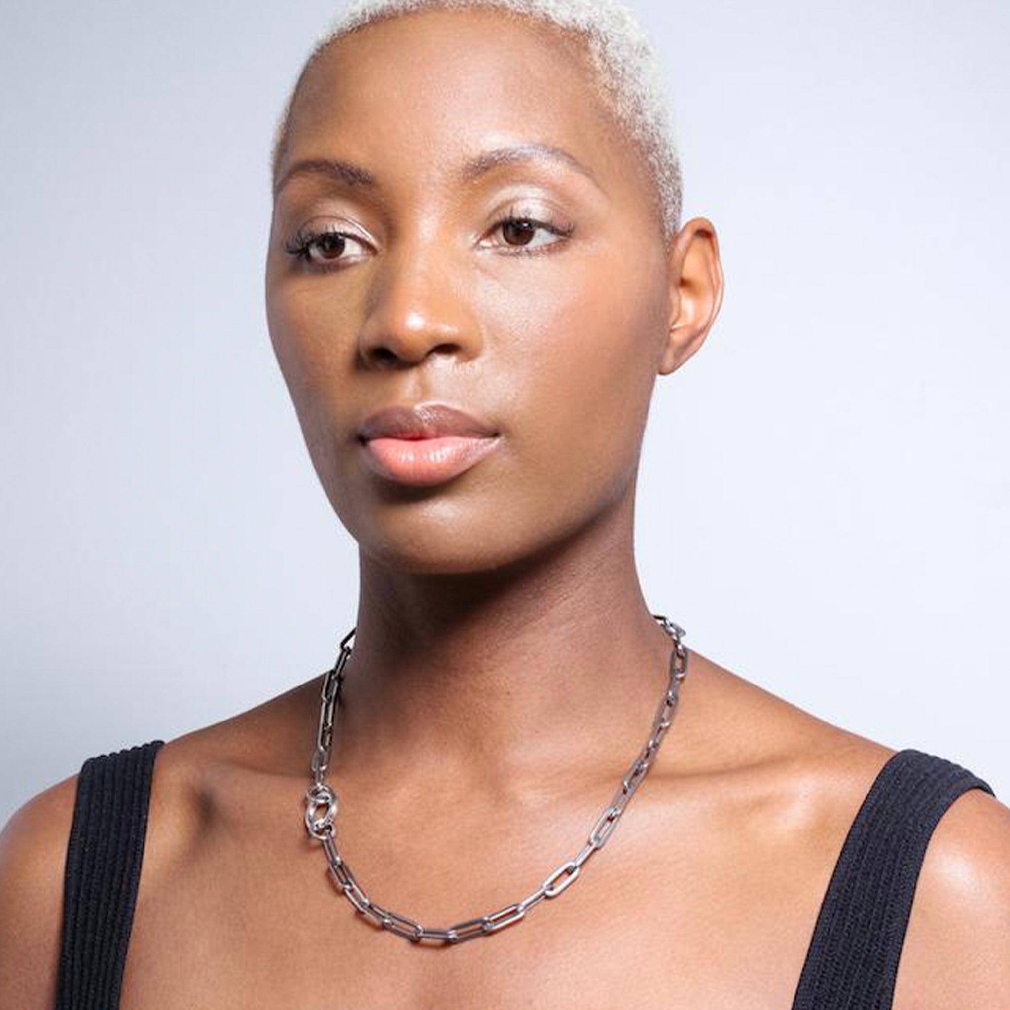 Woman wearing a stainless steel chain necklace on a neutral background
