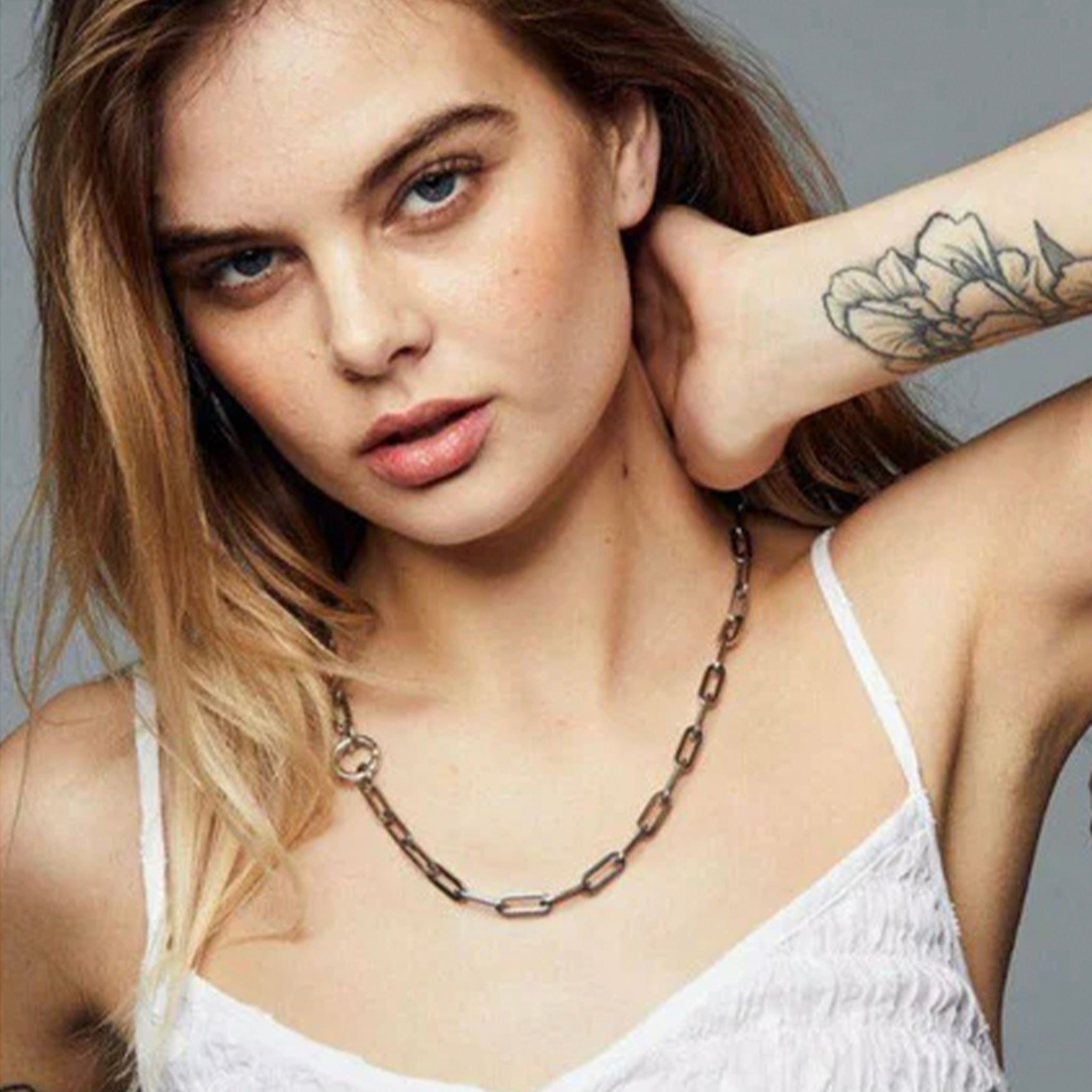 Woman wearing a Gold chain necklace on a grey background