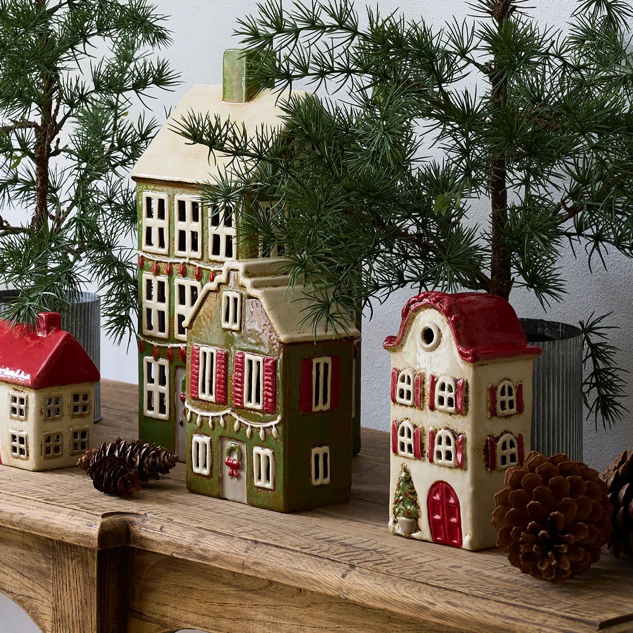 Small ceramic house with green facade, red windows, and white accents on a table.
