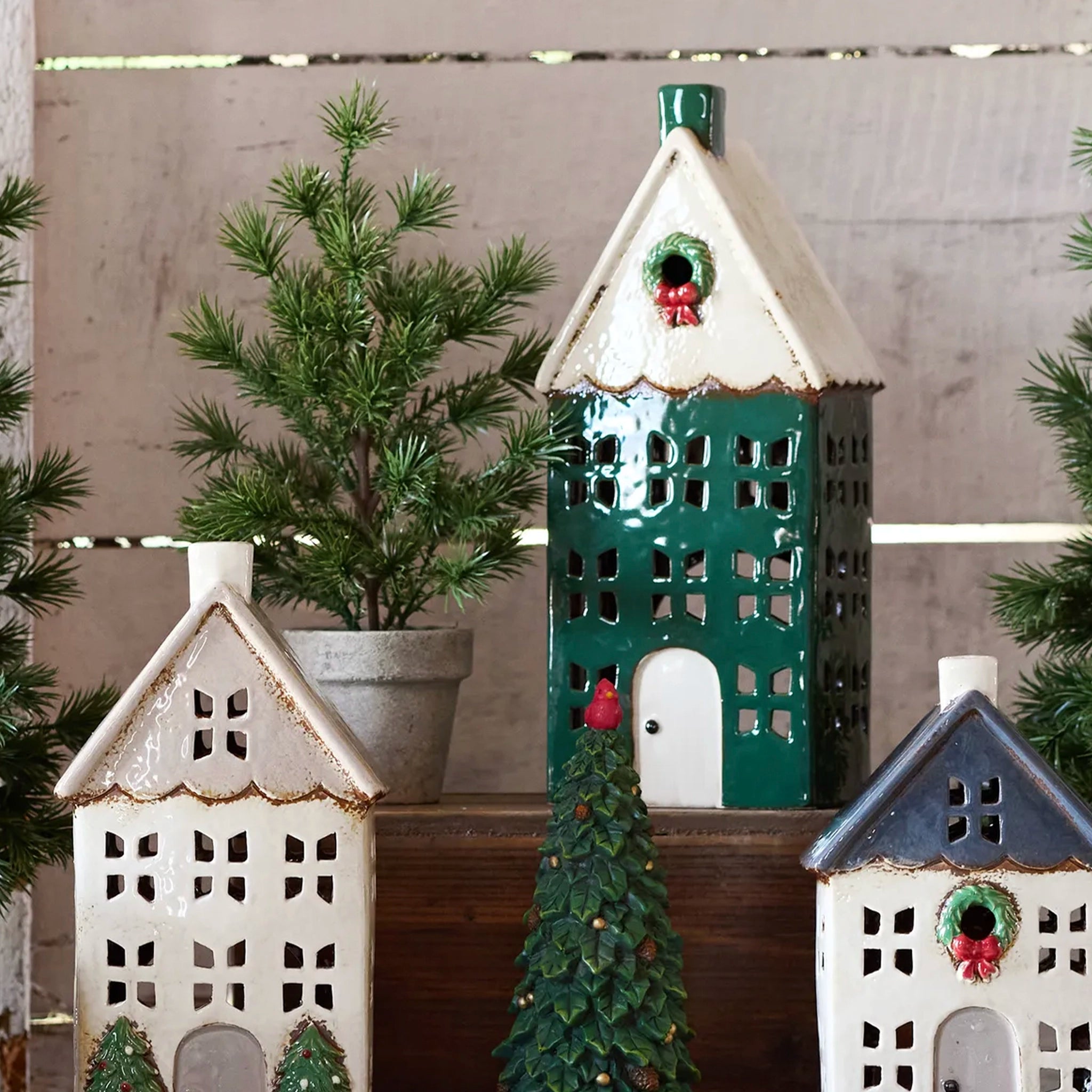 Decorative house-shaped lantern with a green base and white roof on a shelf