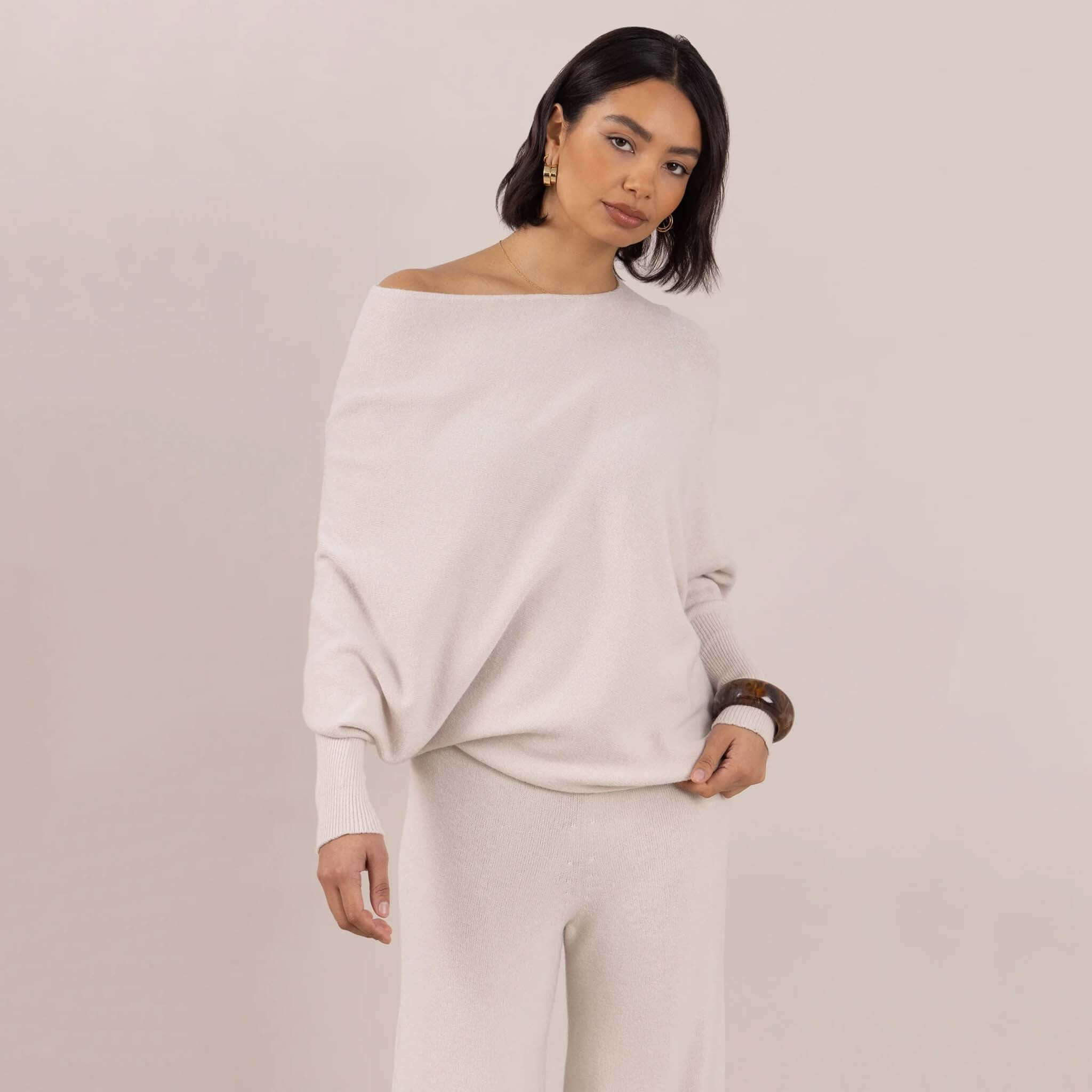 Charli Natalie Asymmetric Sweater - Ivory modeled with stylish batwing sleeves and an off-shoulder neckline.