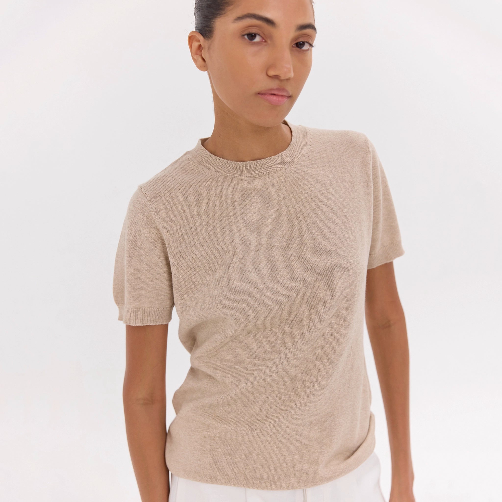 Person wearing a beige t-shirt against a white background