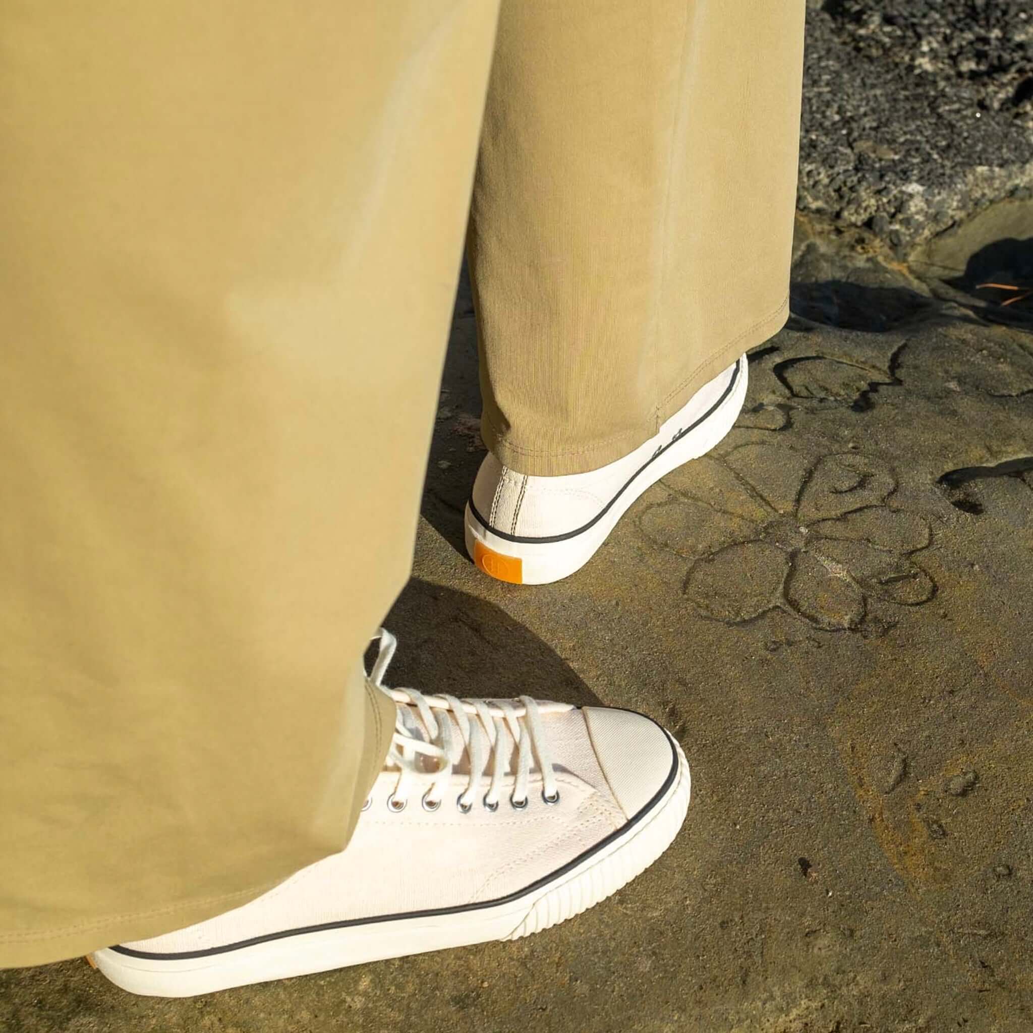 Alt Tag: Collective Canvas Straat Hemp Shoes - Natural & Black worn with beige trousers, organic hemp canvas sustainable sneaker outdoors