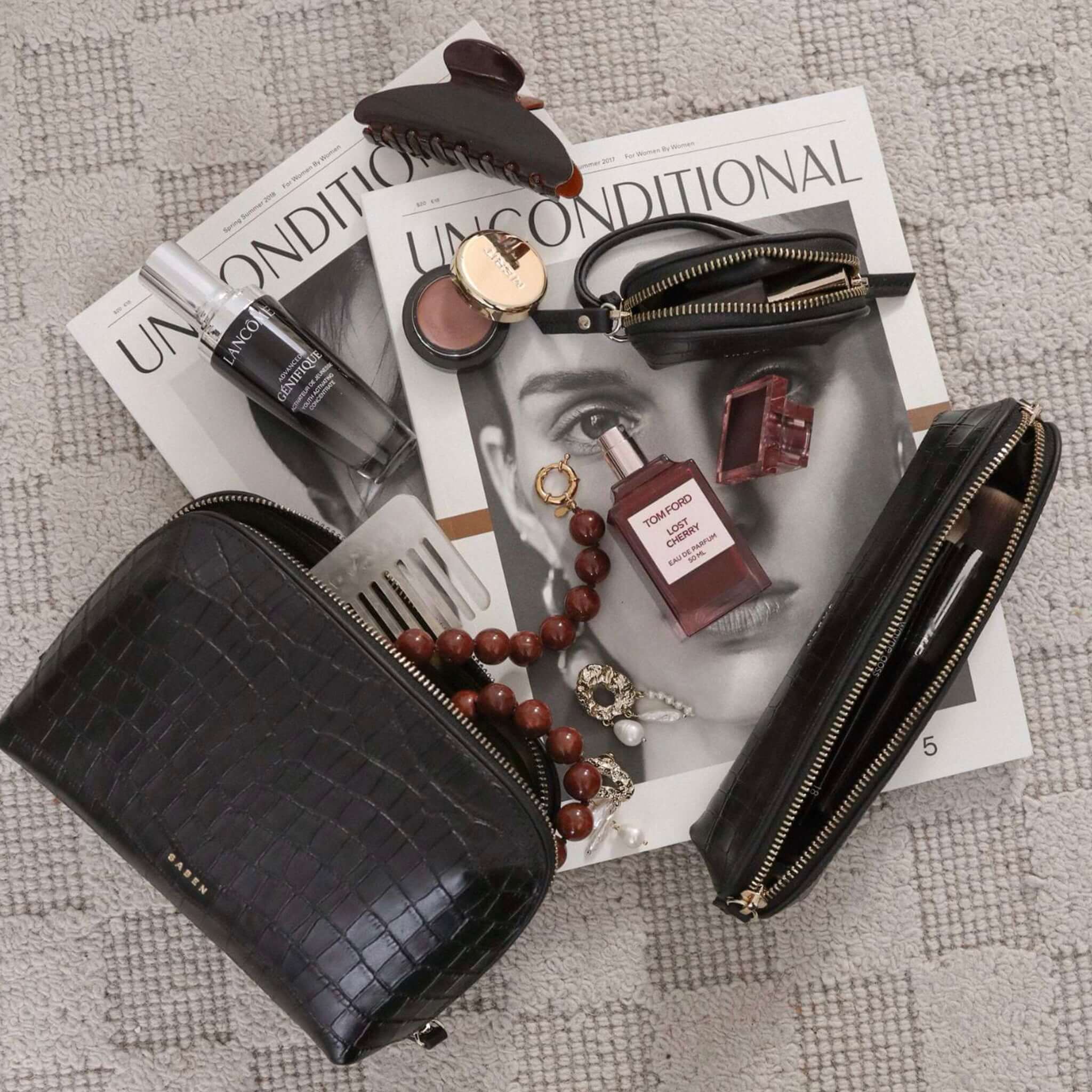 Black handbag with makeup items on a magazine
