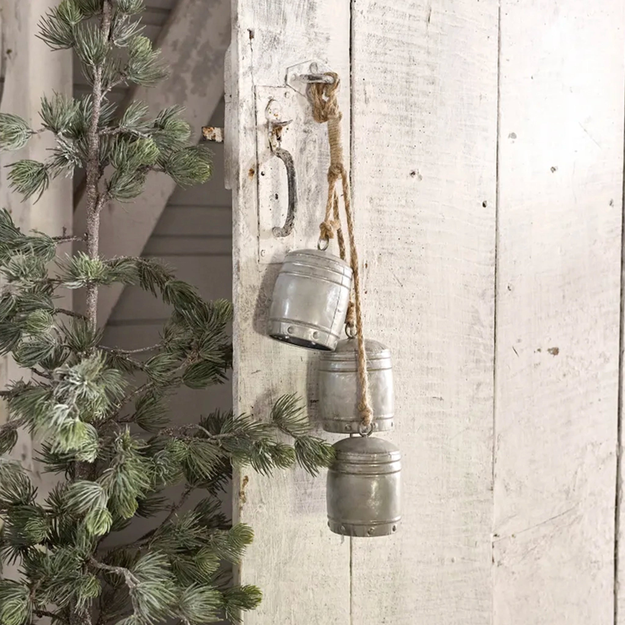 Decorative metal buckets hanging on a rustic wooden wall with a Christmas tree.