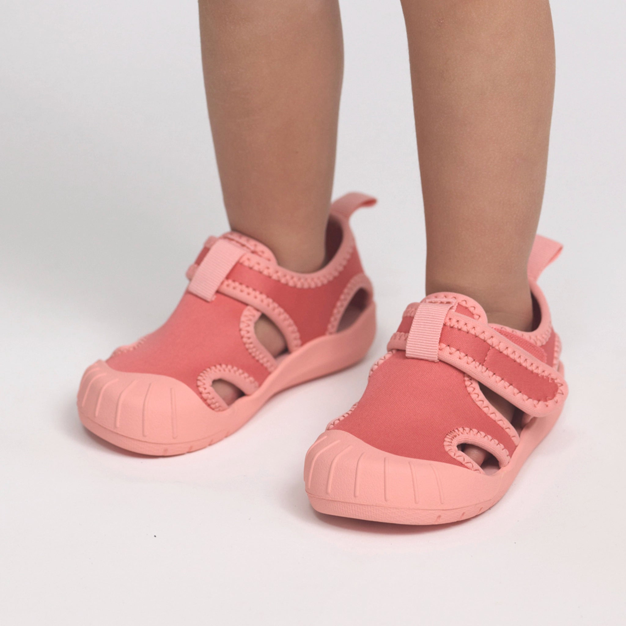 Child wearing a pair of pink children's sandals on a white background