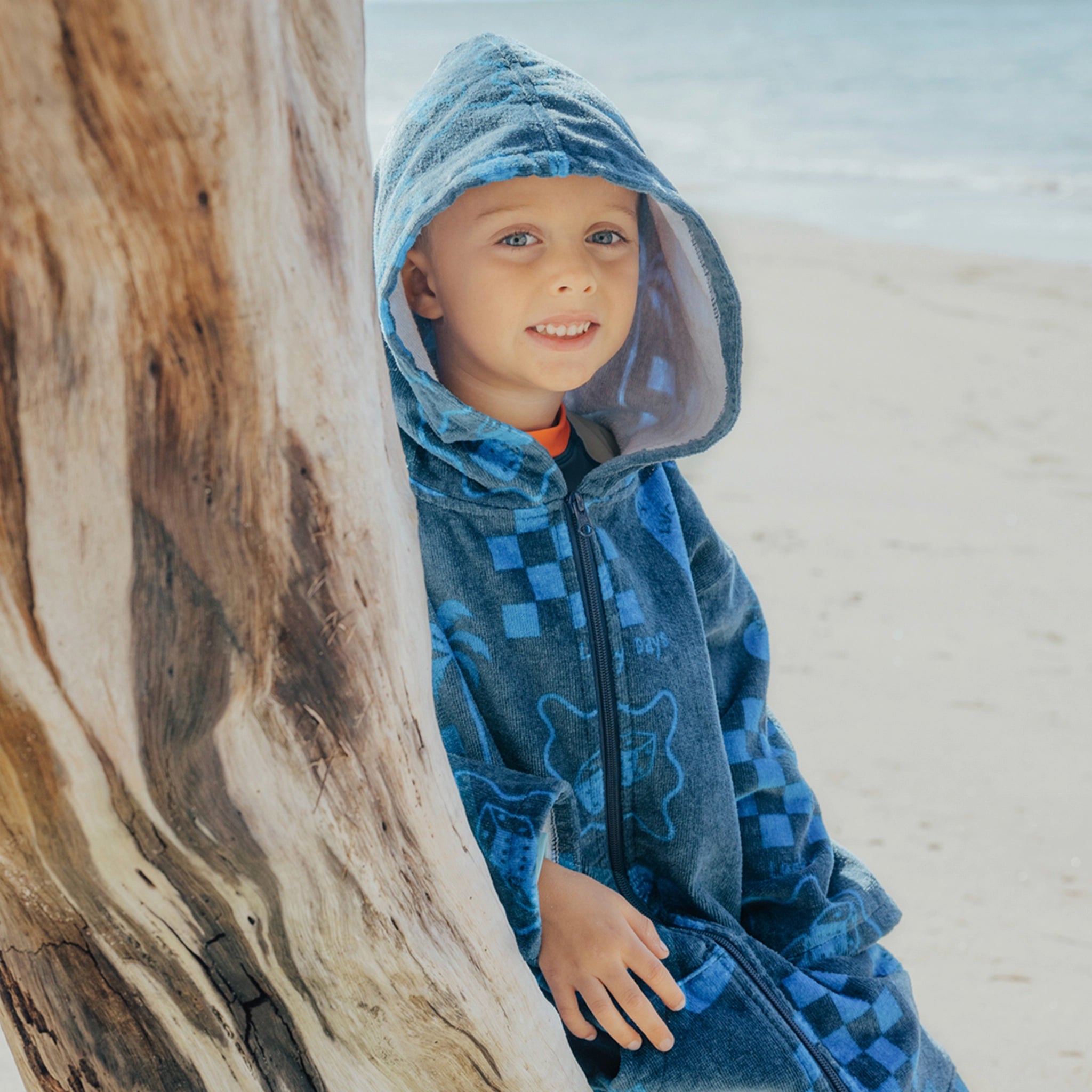 Child wearing a dark blue children's zip up towel at a beach