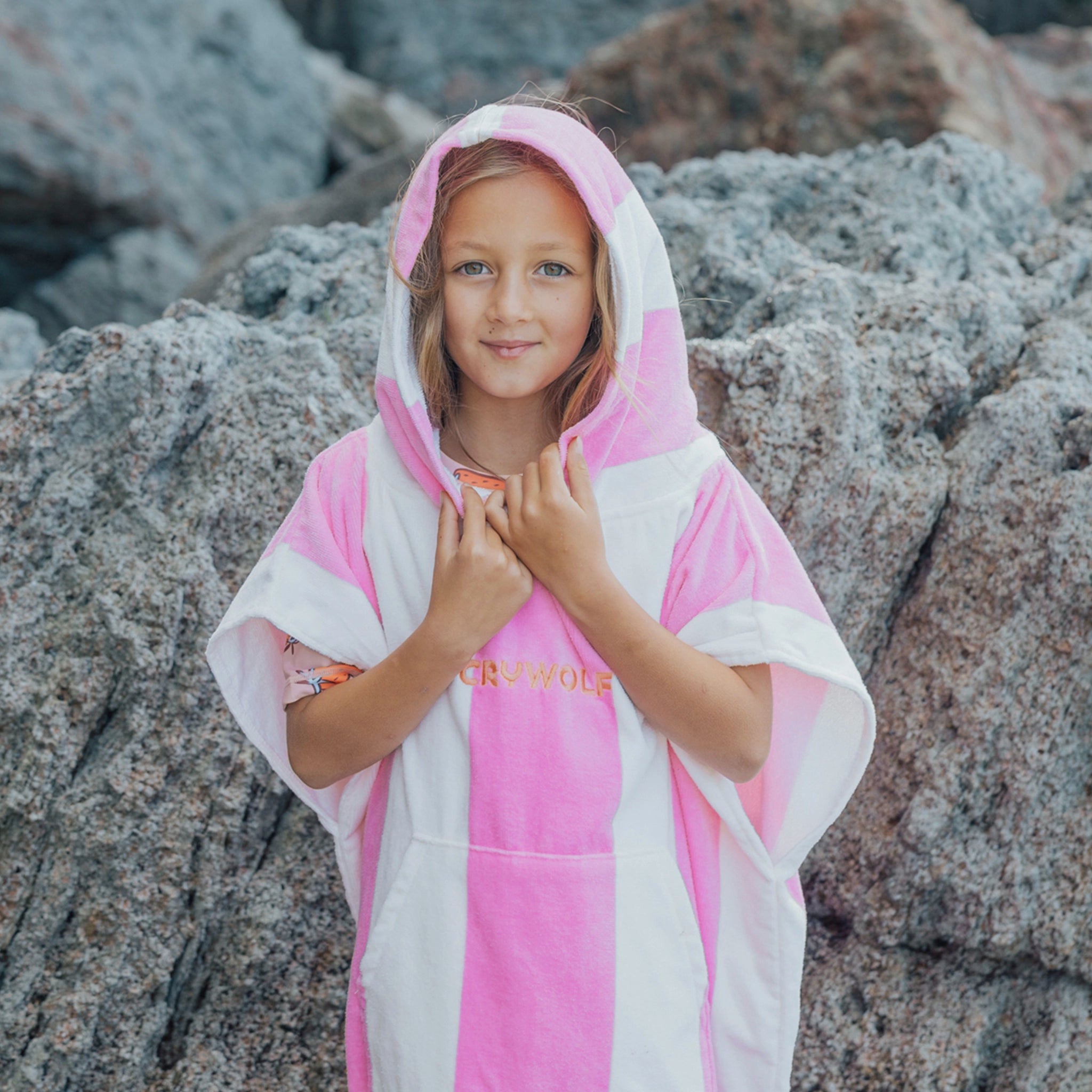 Young girl wearing a pink and white striped towel on rocky terrain