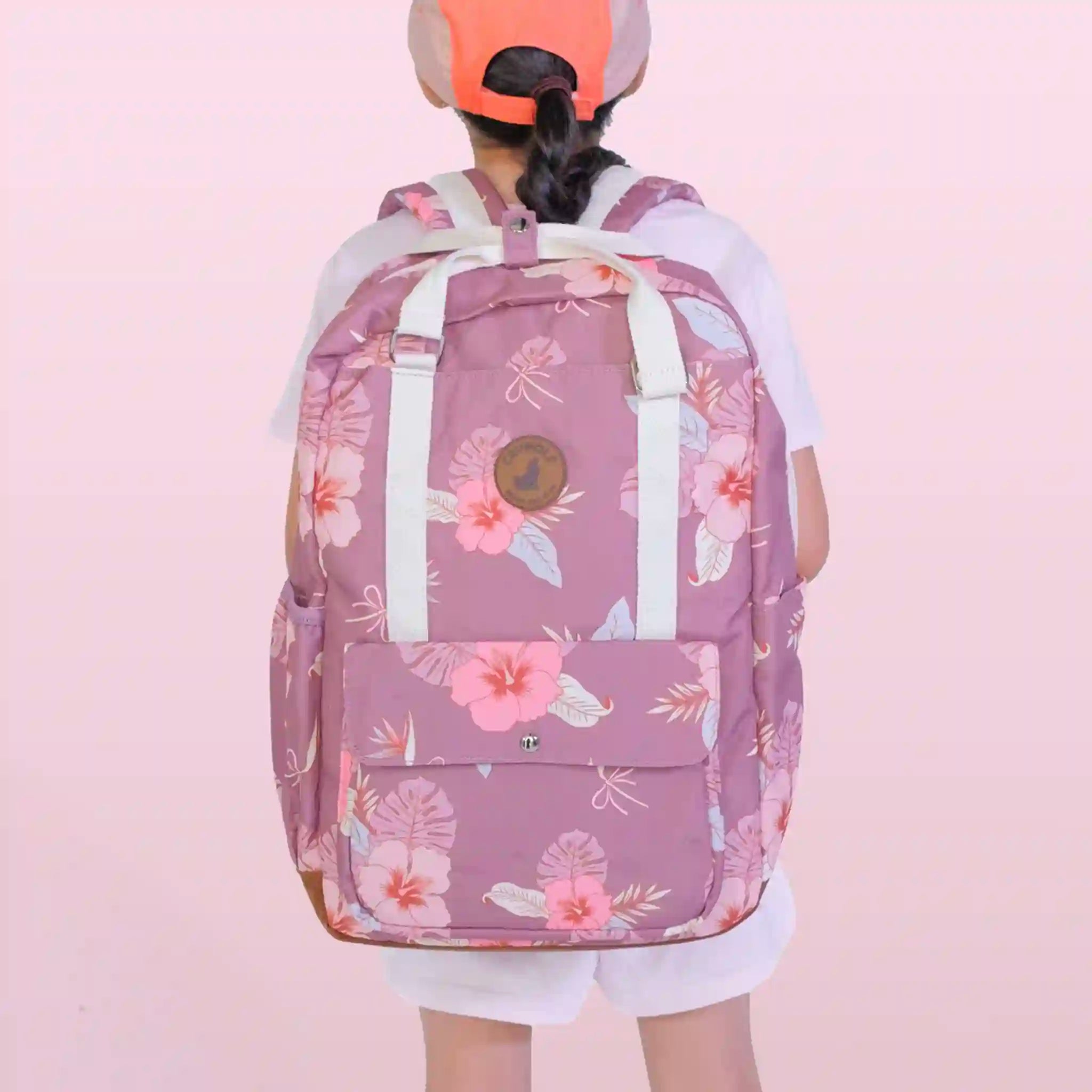 Person wearing a pink floral backpack on a pink background