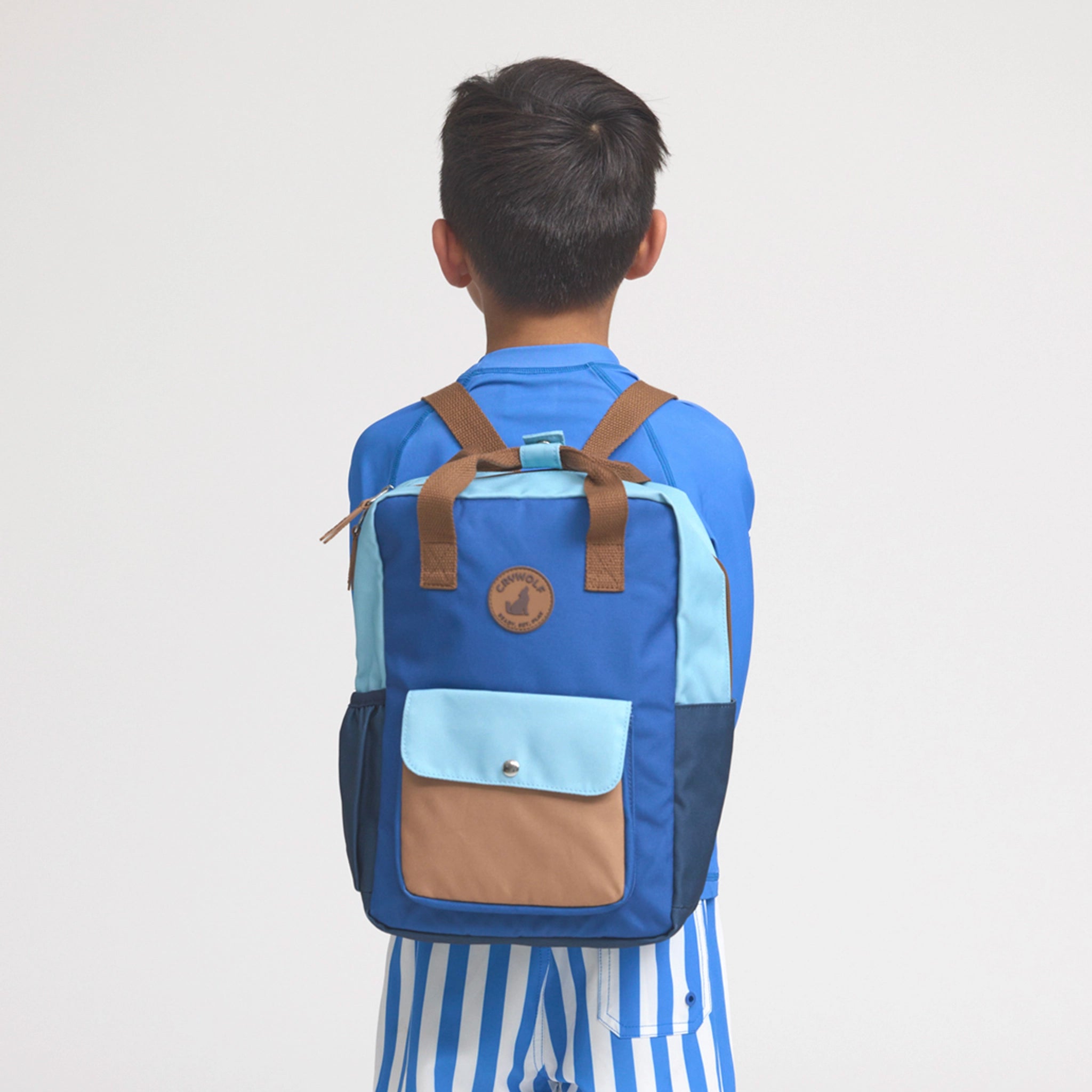 Person wearing a blue and brown backpack on a plain background