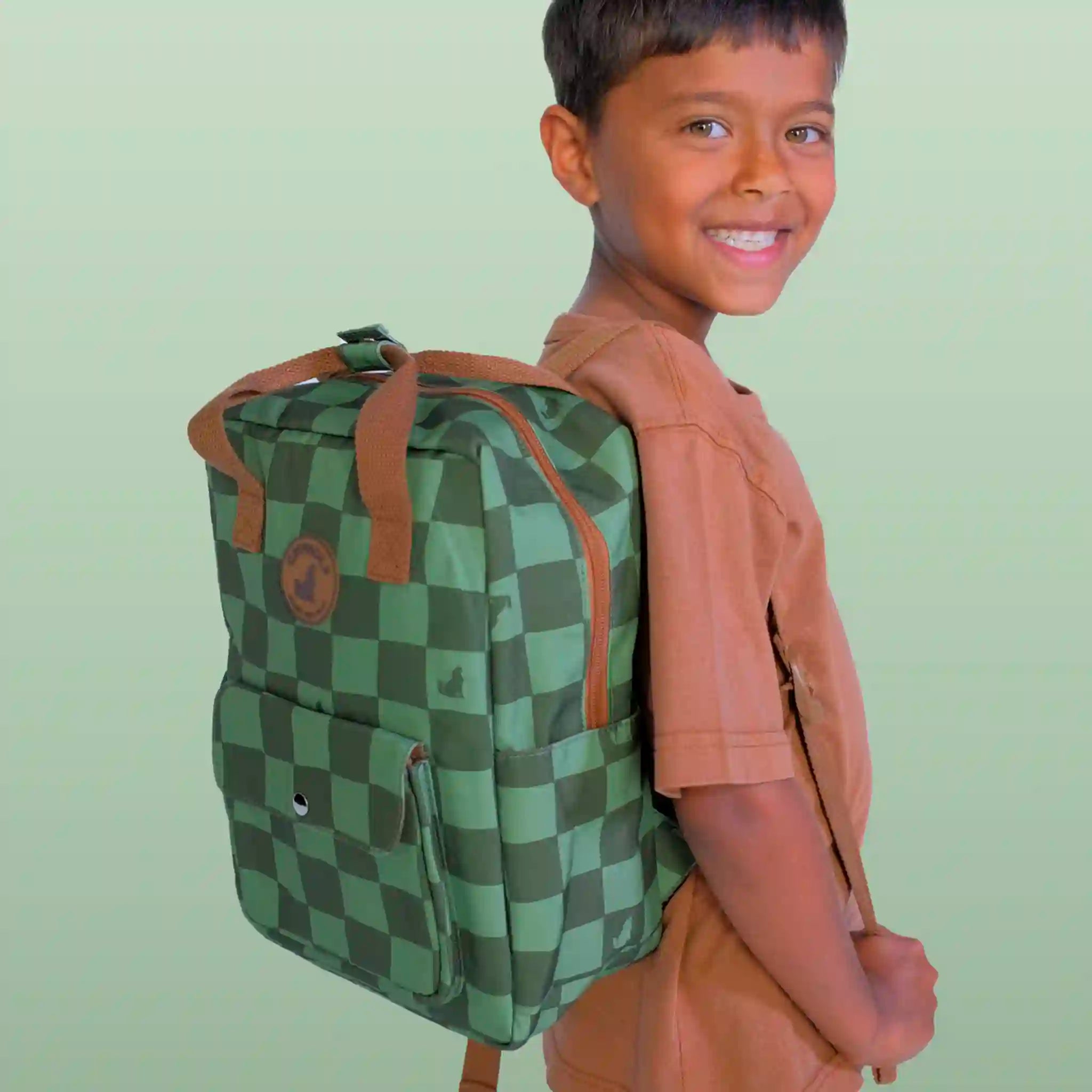 Child wearing a green checkered backpack against a light green background