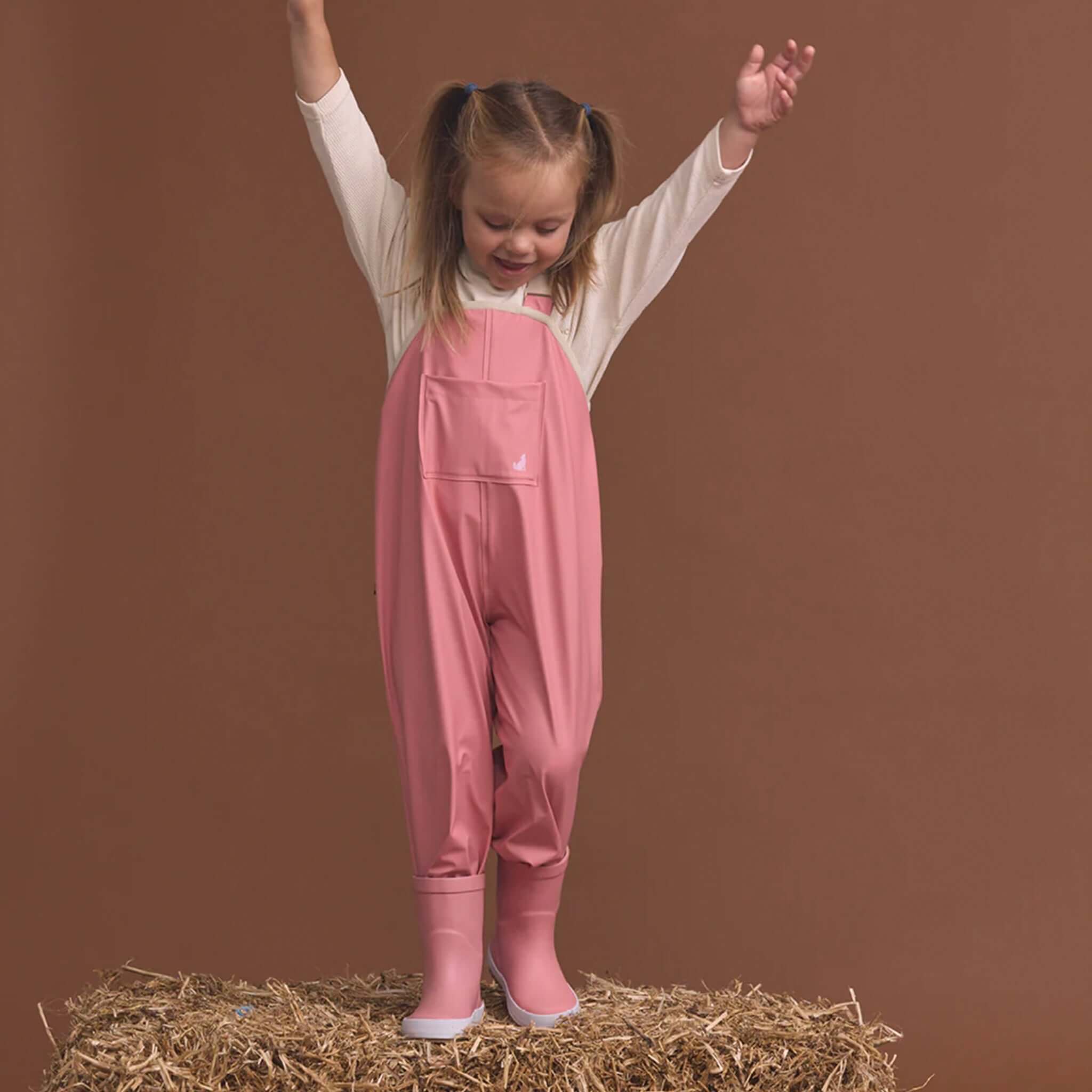 Alt Tag: Crywolf Rain Overalls - Rose on child, fully waterproof adjustable rain bib overalls for outdoor play and kindy