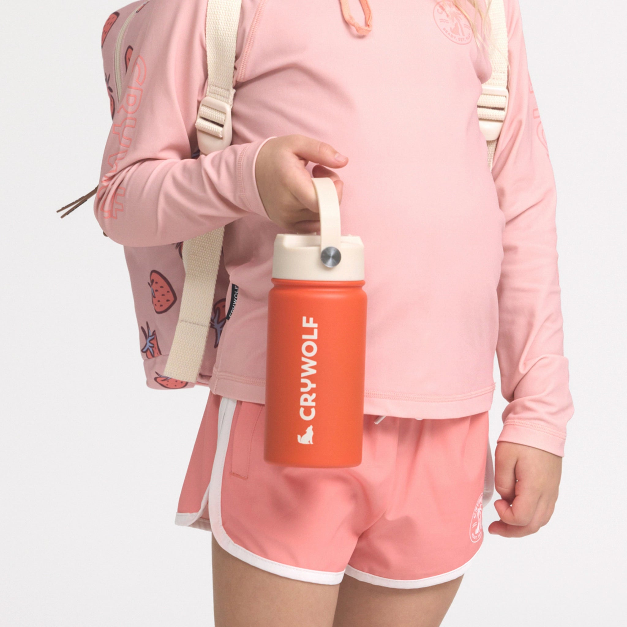 Person wearing a pink outfit holding an orange water bottle with 'CRYWOLF' branding.