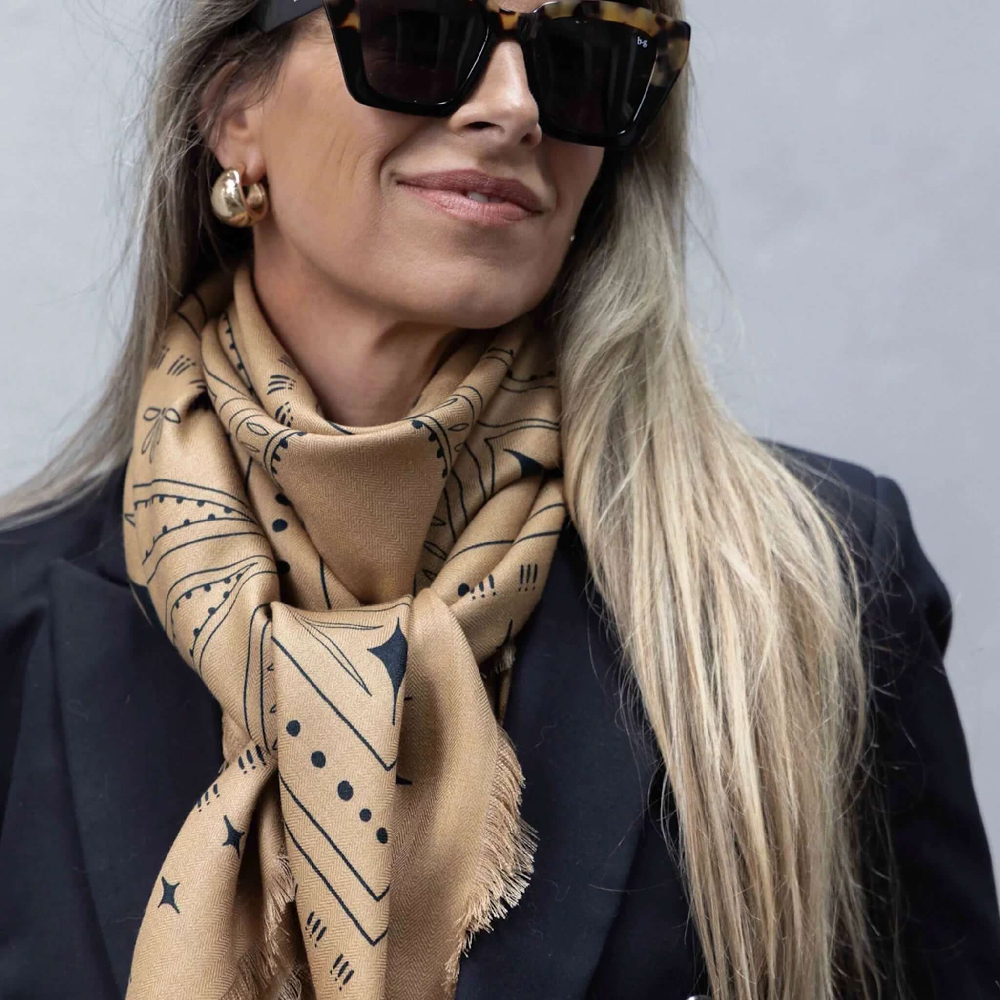 Dark Hampton x Ellie Compton The Holden Wool Silk Scarf worn elegantly with a stylish outfit, featuring intricate tan and navy design.