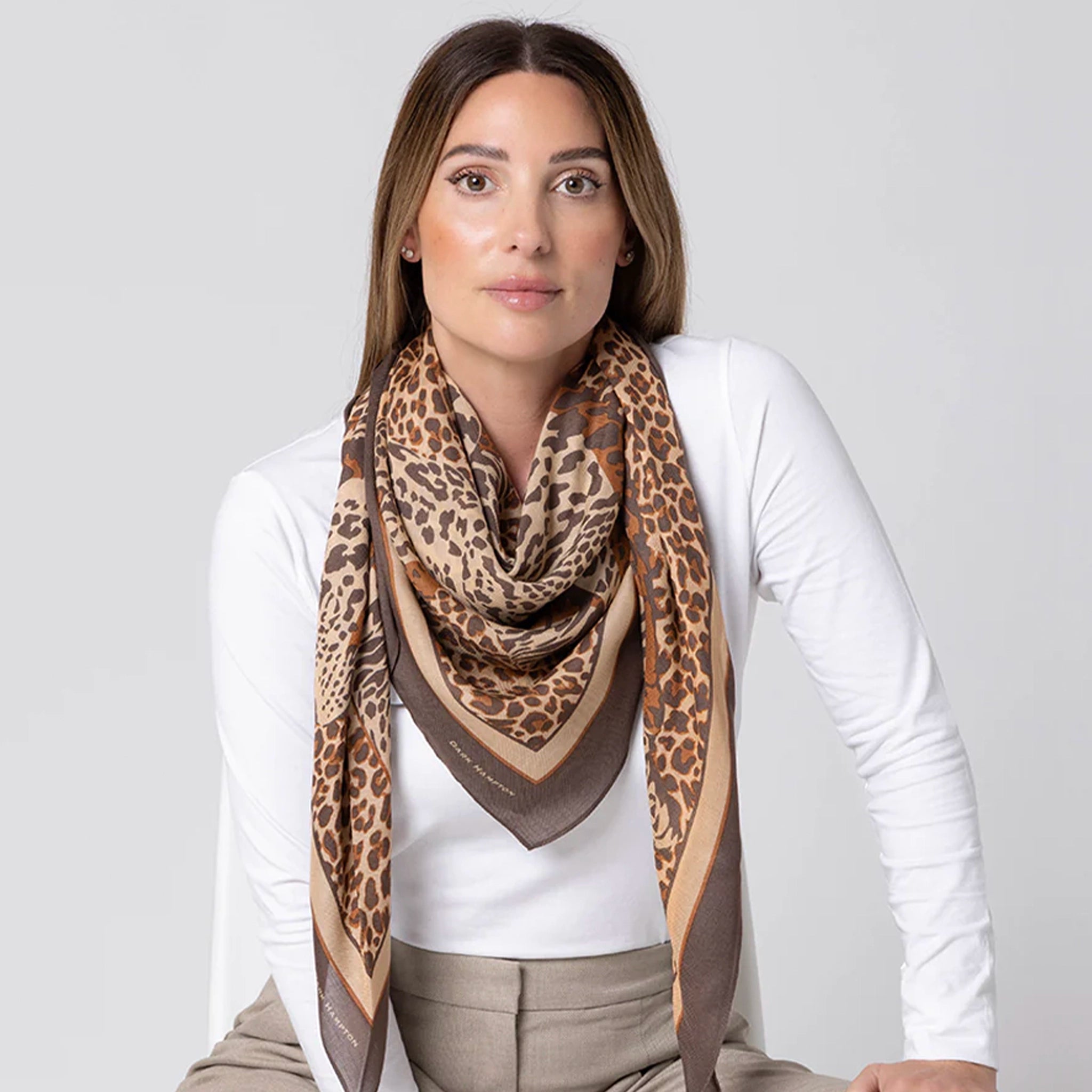Woman wearing a leopard print scarf on a plain background
