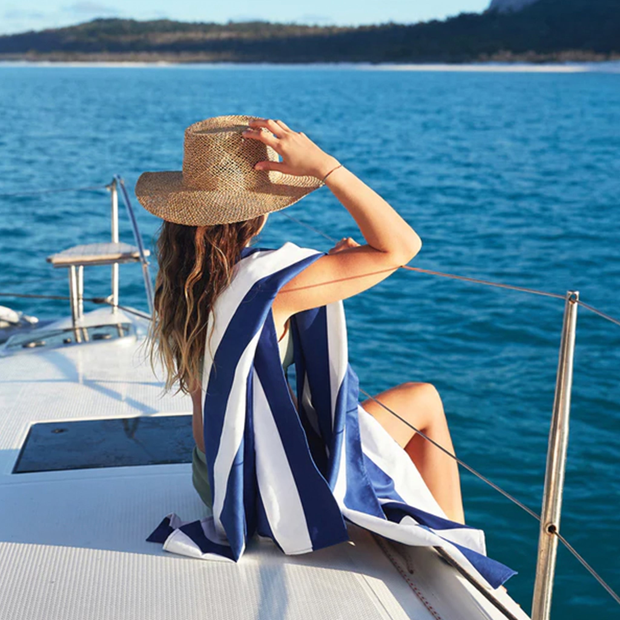 Woman on a boat with a striped beach towel.