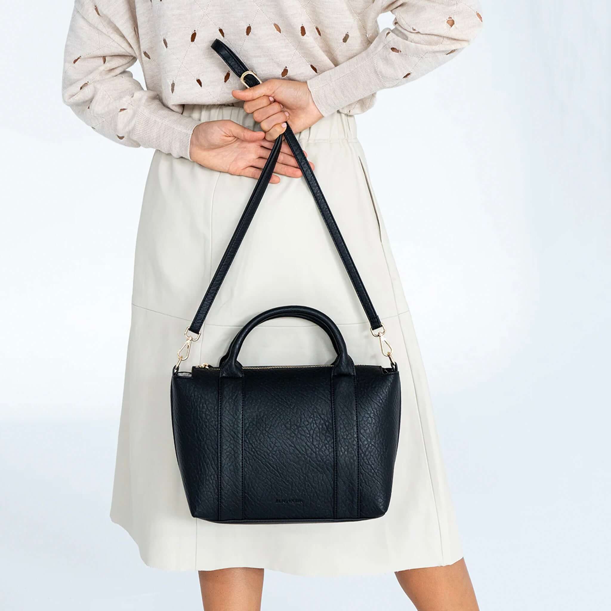 Alt Tag: Elms+King Messina Tote - Black structured recycled PU tote with top handles and removable crossbody strap, worn crossbody