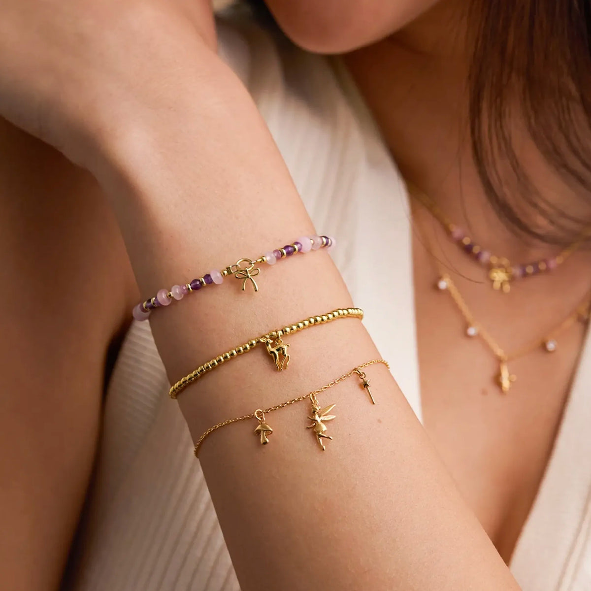 Estella Bartlett Fairy Charm Bracelet worn on the wrist, layered with beaded bracelets