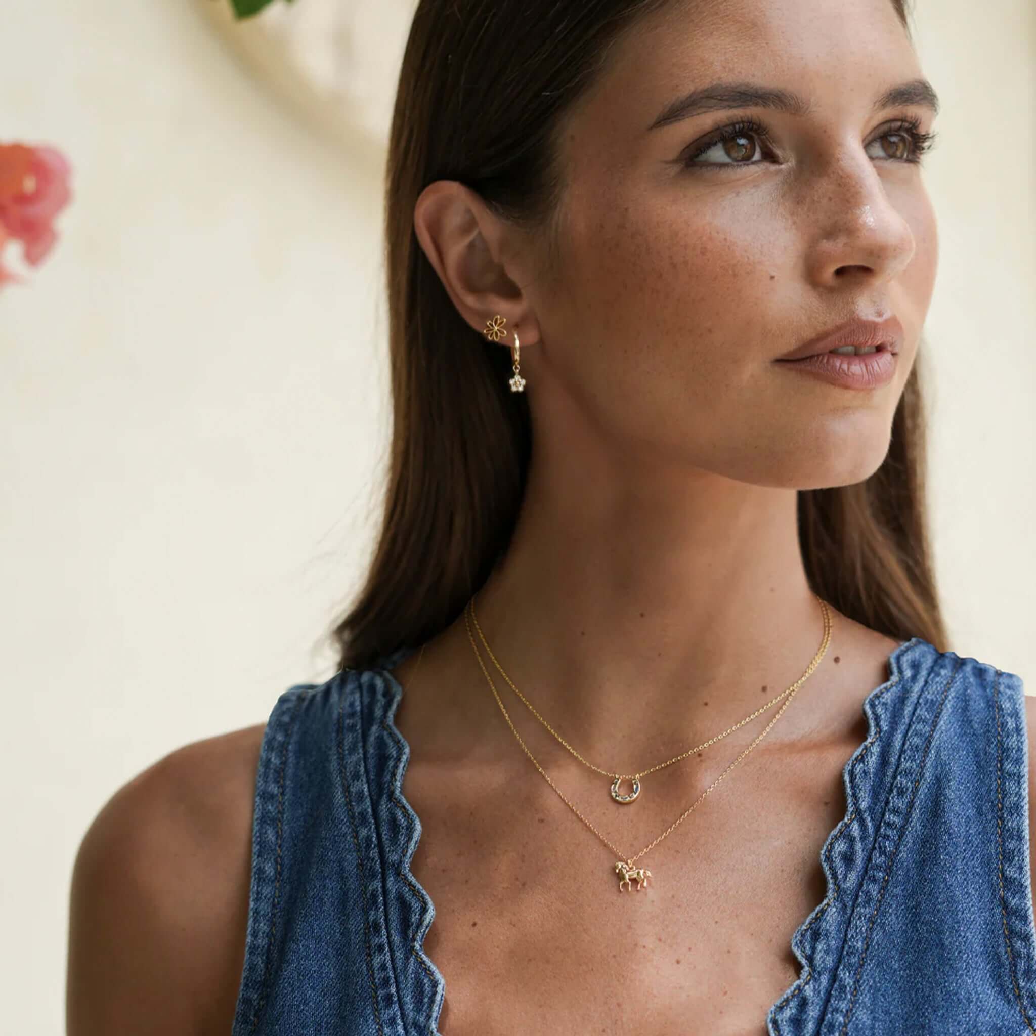 Alt Tag: Estella Bartlett Horse Necklace - Gold Plated worn layered on model, delicate gold-plated trotting horse pendant necklace