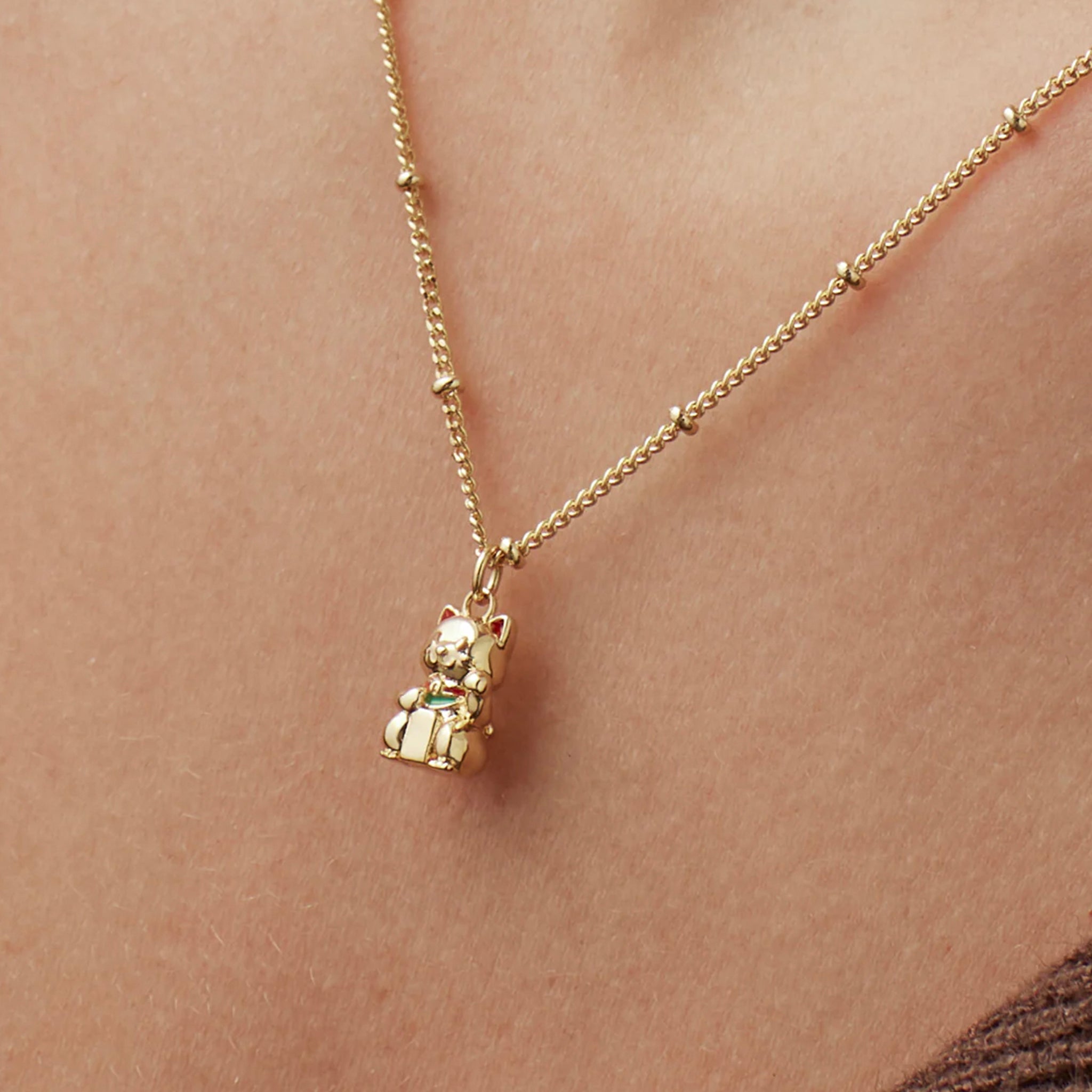 Gold necklace with a small pendant on a person's neck