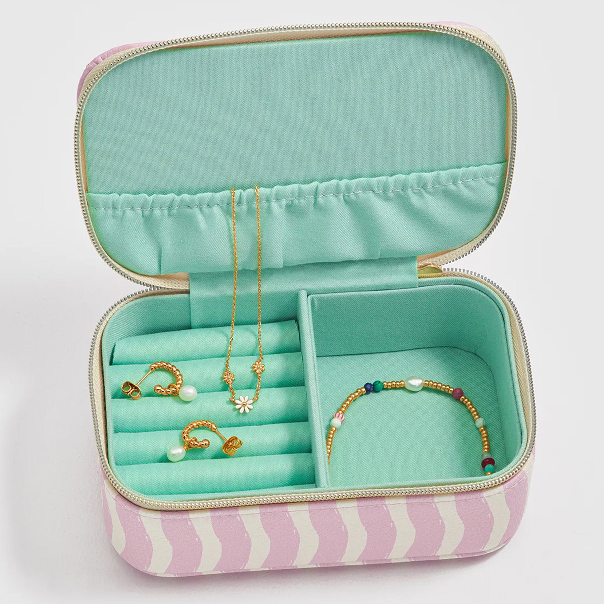 Pink jewelry box with striped pattern and gold zipper on a light gray background