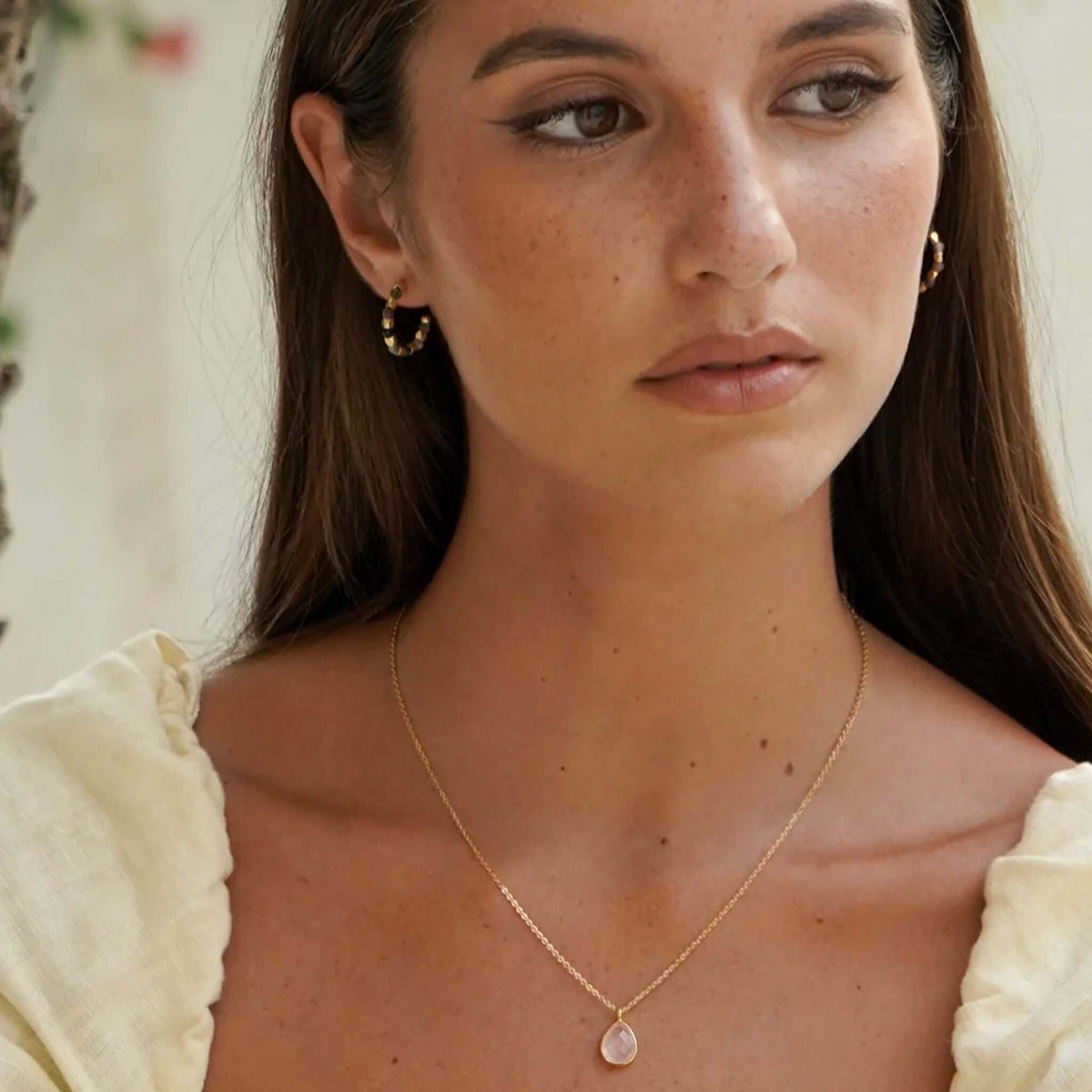 Estella Bartlett Wellness Faceted Teardrop Necklace - Rose Quartz worn by model with dainty gold chain and rose quartz pendant.