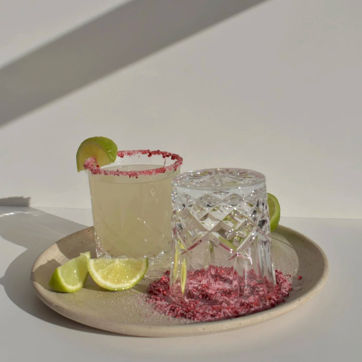 F N Lemons Rim Dust - Raspberry Sugar on a margarita rim with lime wedges and a dipping plate