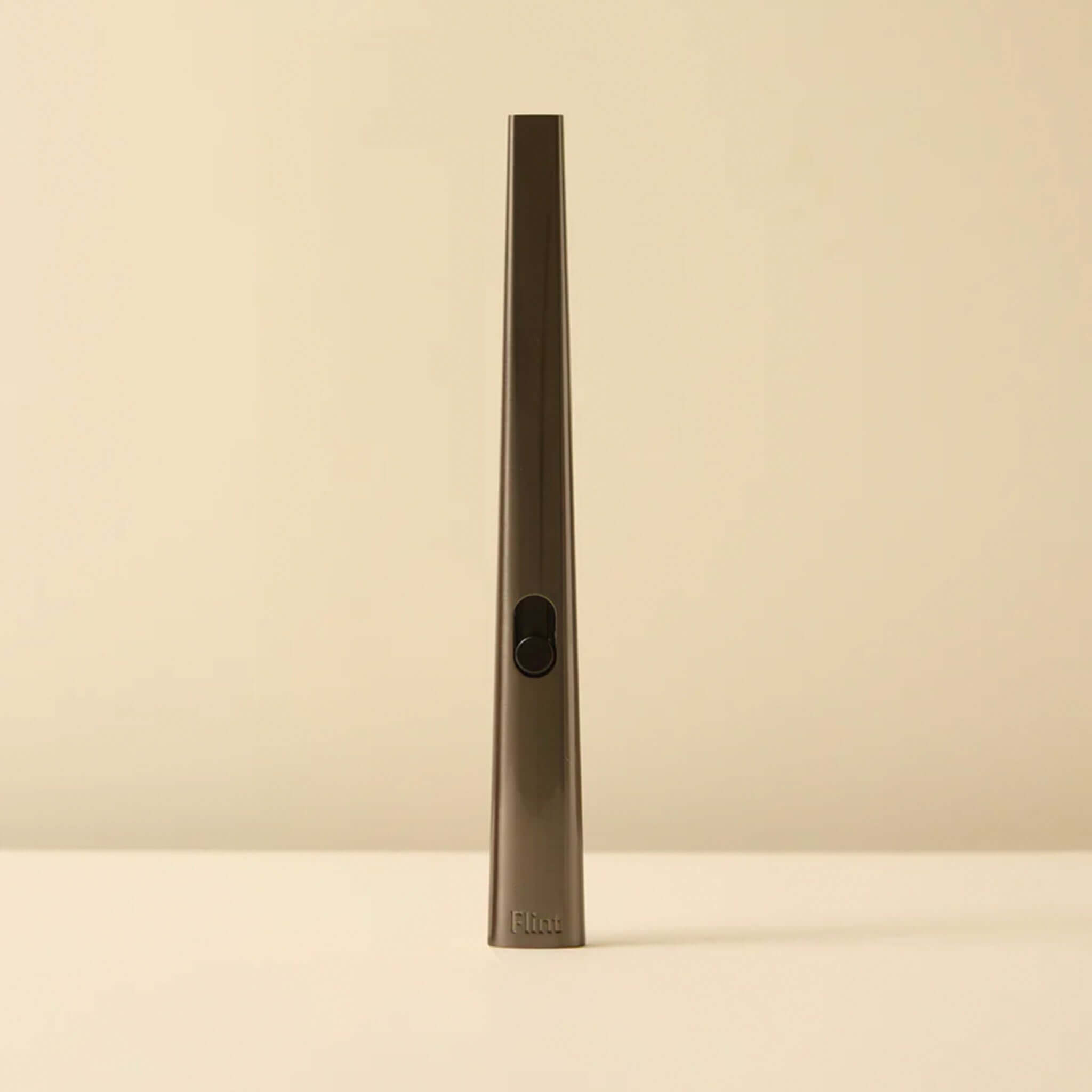 Tall, thin gunmetal metallic lighter on a beige background