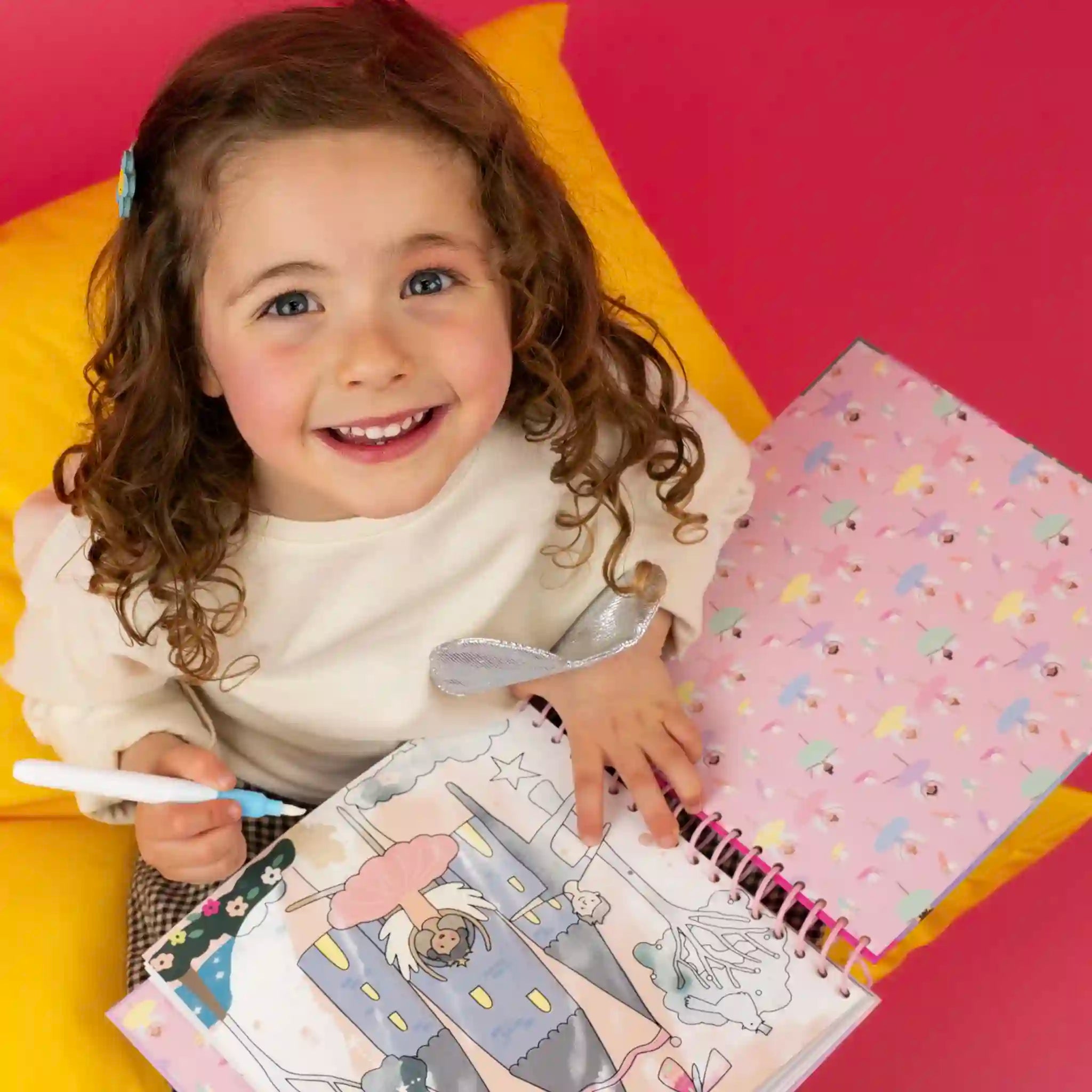 Child coloring in a book with a pink background