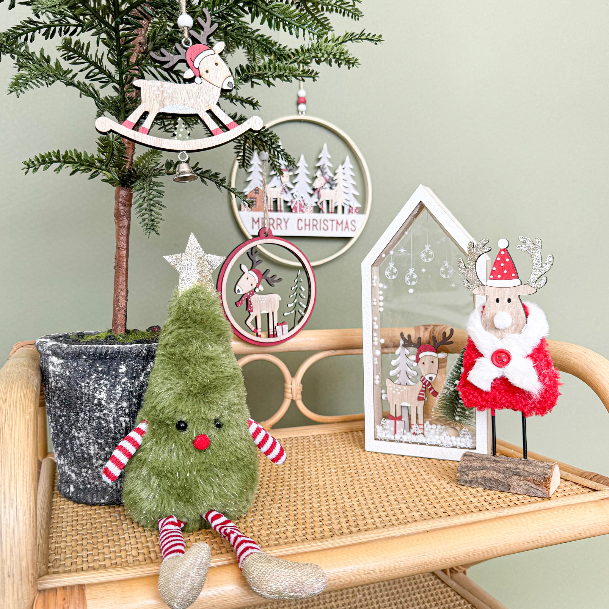Green plush toy with red and white striped legs on a white cane table.
