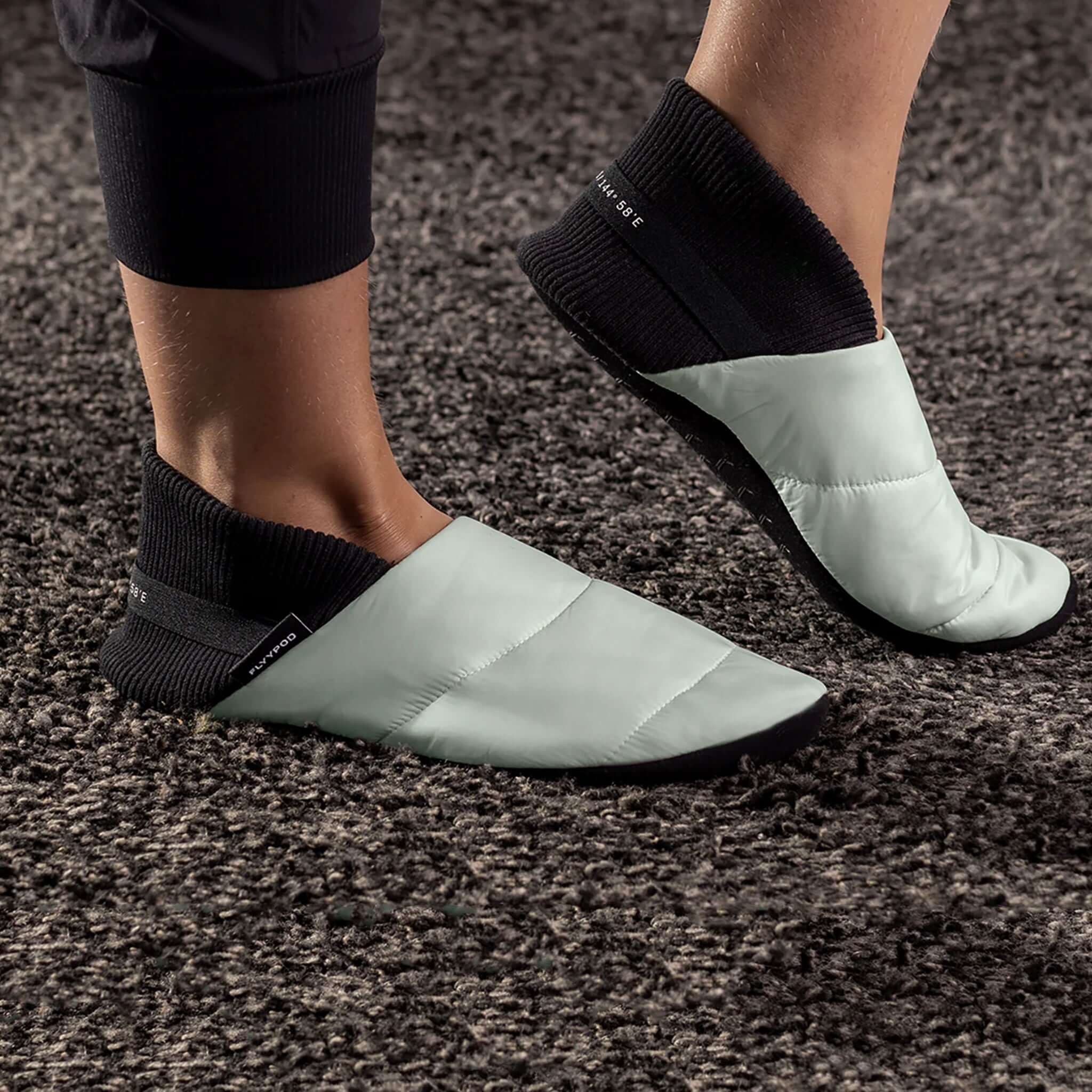 Alt Tag: Flyypod Skyywalkers Travel Slippers - Mist worn on feet, mint puffer travel slippers with black socks for flights, hotel, home comfort