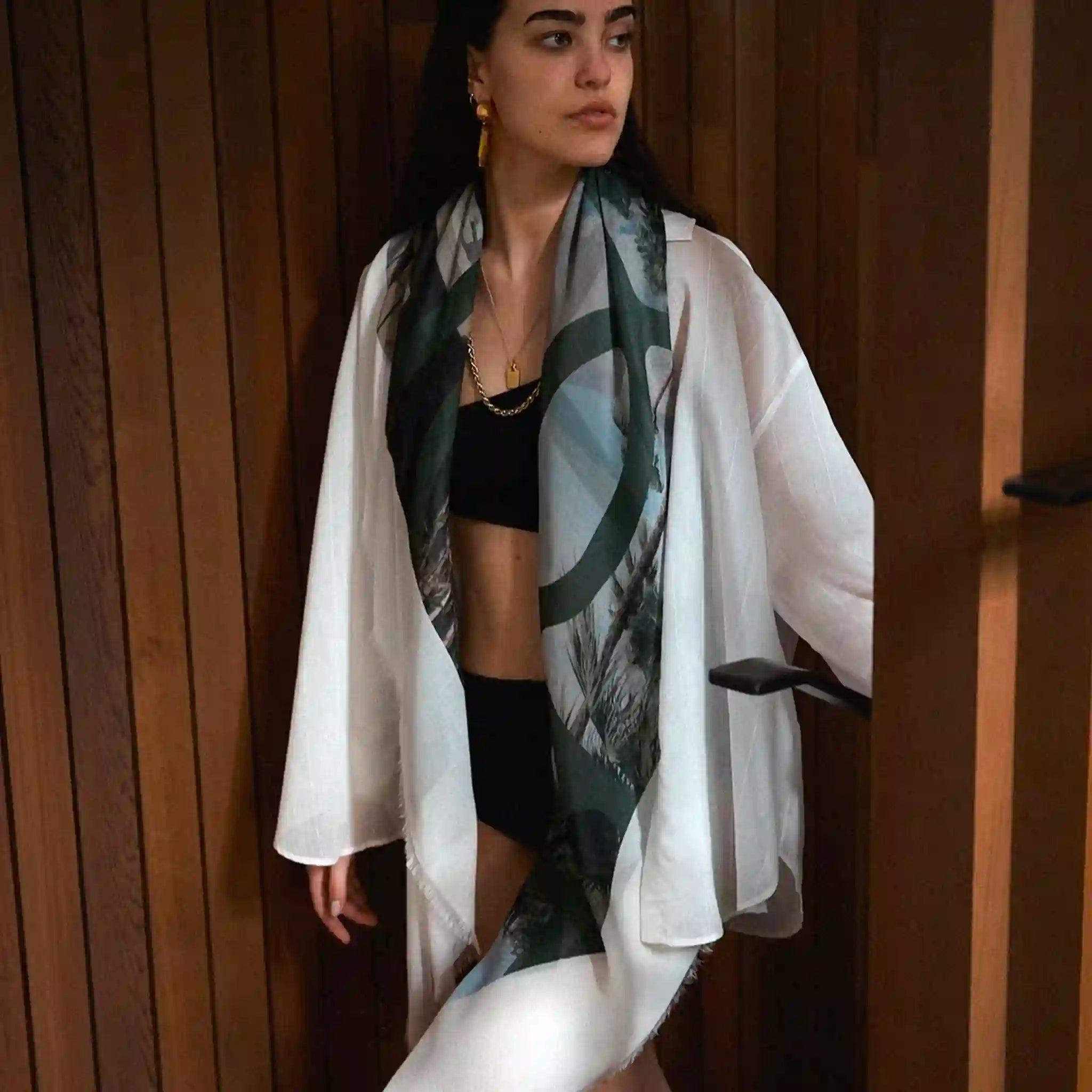 Woman wearing a white kimono with a black and green patterned scarf against a wooden background