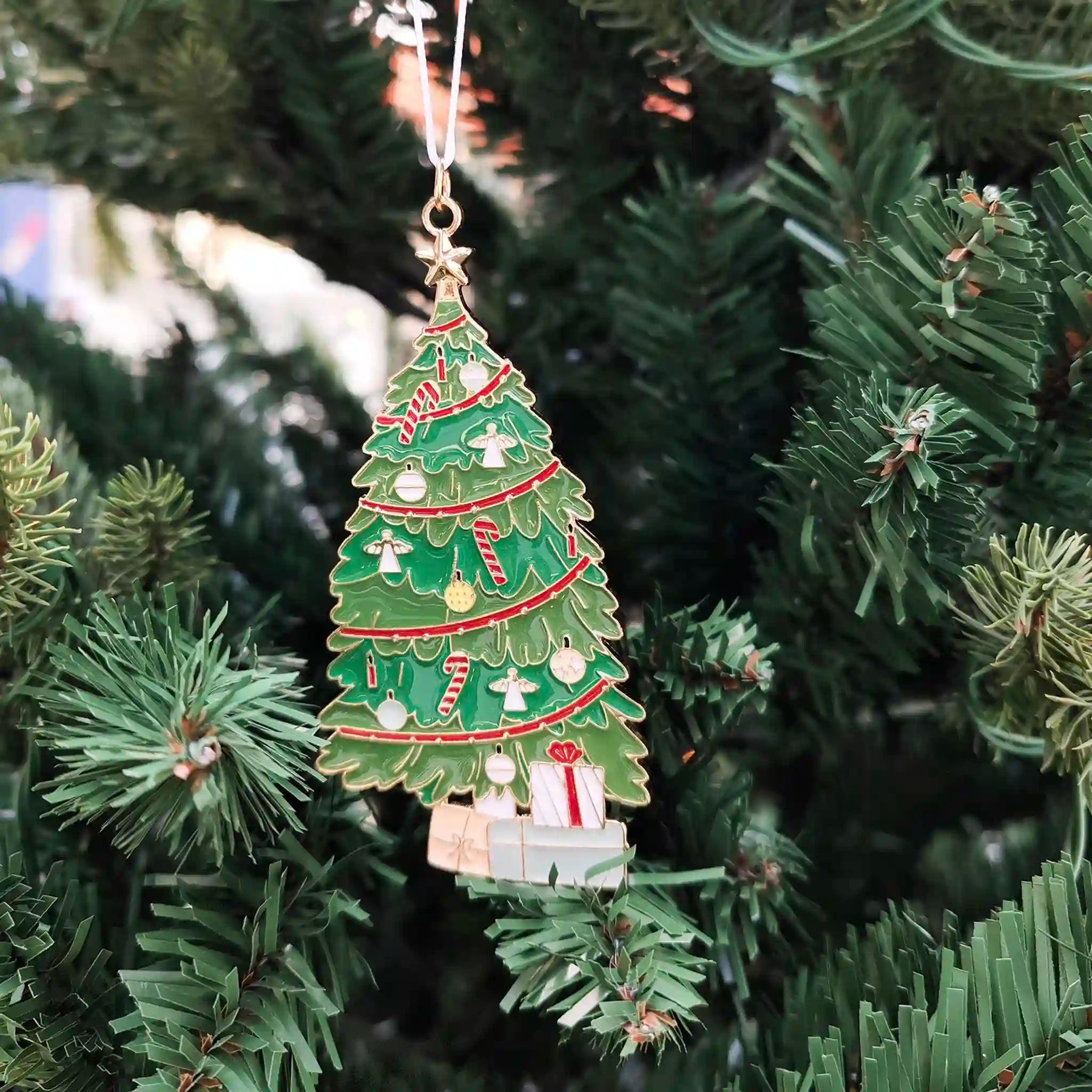 Decorative Christmas tree ornament with presents on a green Christmas tree.