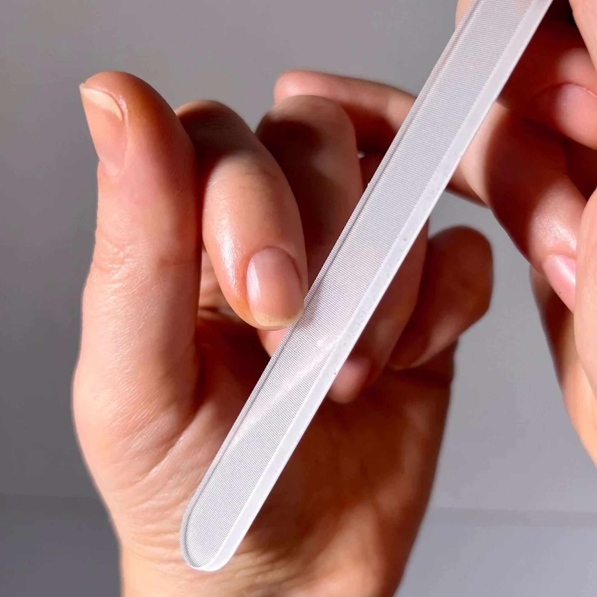 Alt Tag: Hanami Nano Glass Nail File & Buffer in hand filing natural nails, tempered nano-glass tool for shaping, buffing and shine