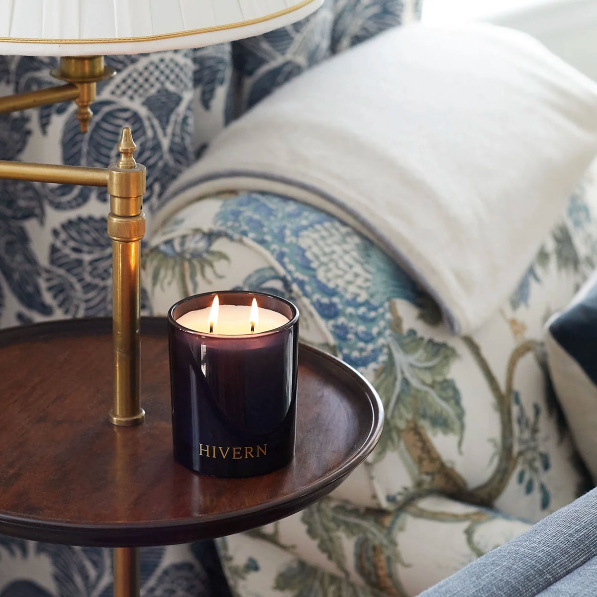Hivern soy candle lit in a dark glass vessel on a side table