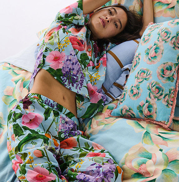 Woman lying on a bed with floral bedding and pillows